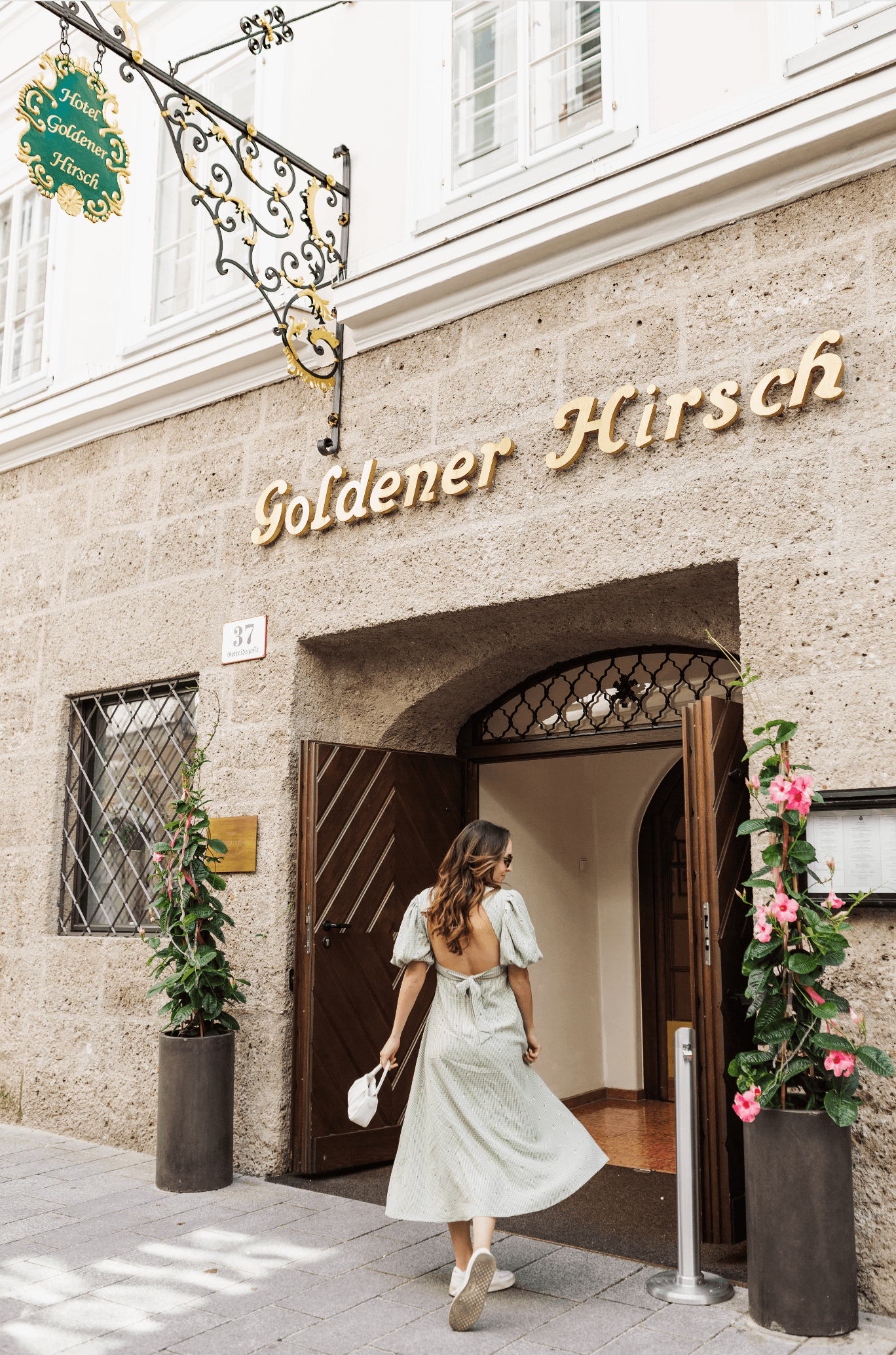 Merissa posing in a green dress in front of a stone storefront outside.