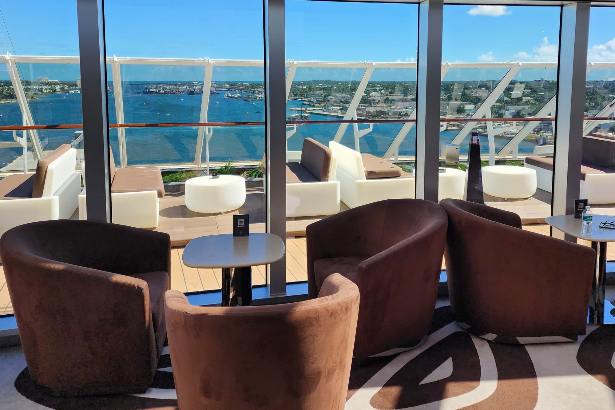 chairs and tables on a bright cruise ship deck overlooking the ocean