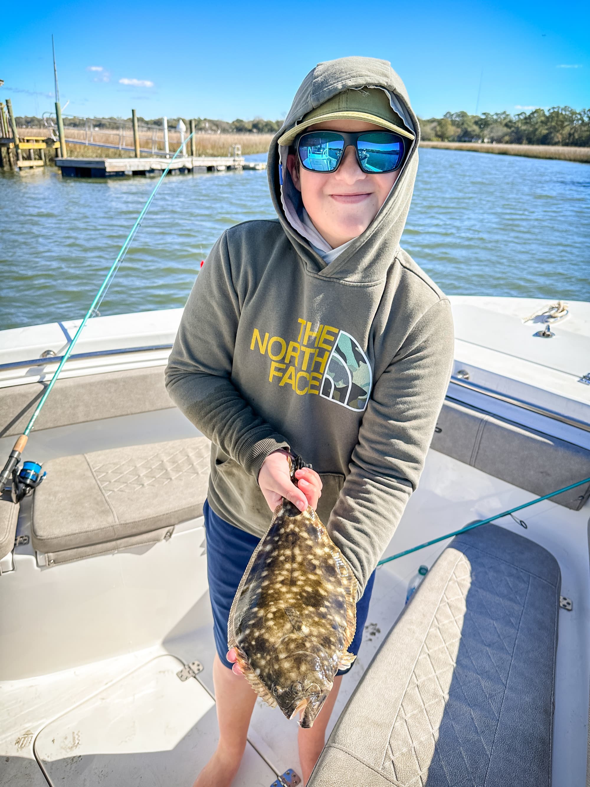 A picture of a person on a boat holding a fish during the daytime.