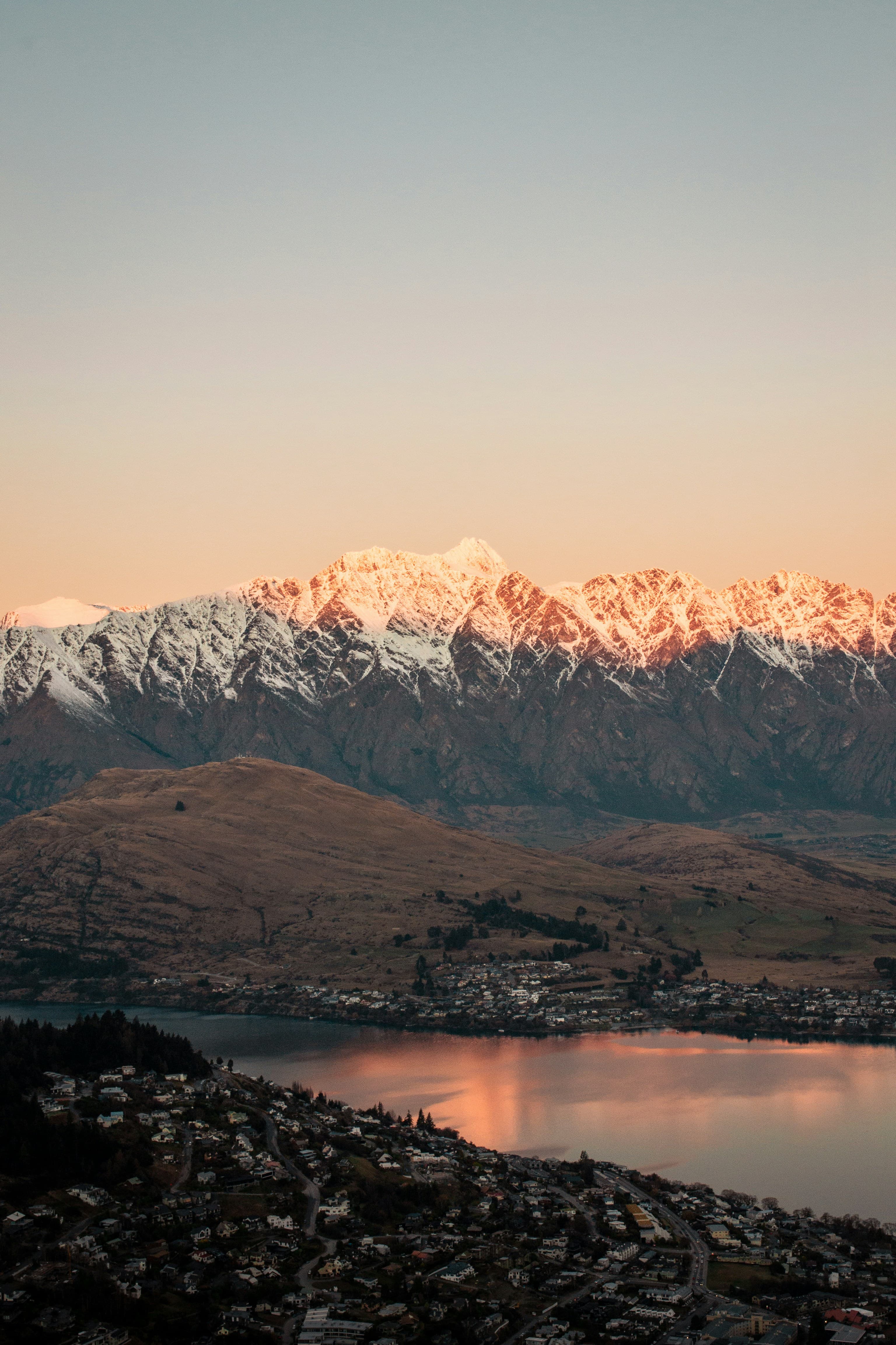 A beautiful view looking out to a rocky lake with mountains with the setting on the snow covered peaks.