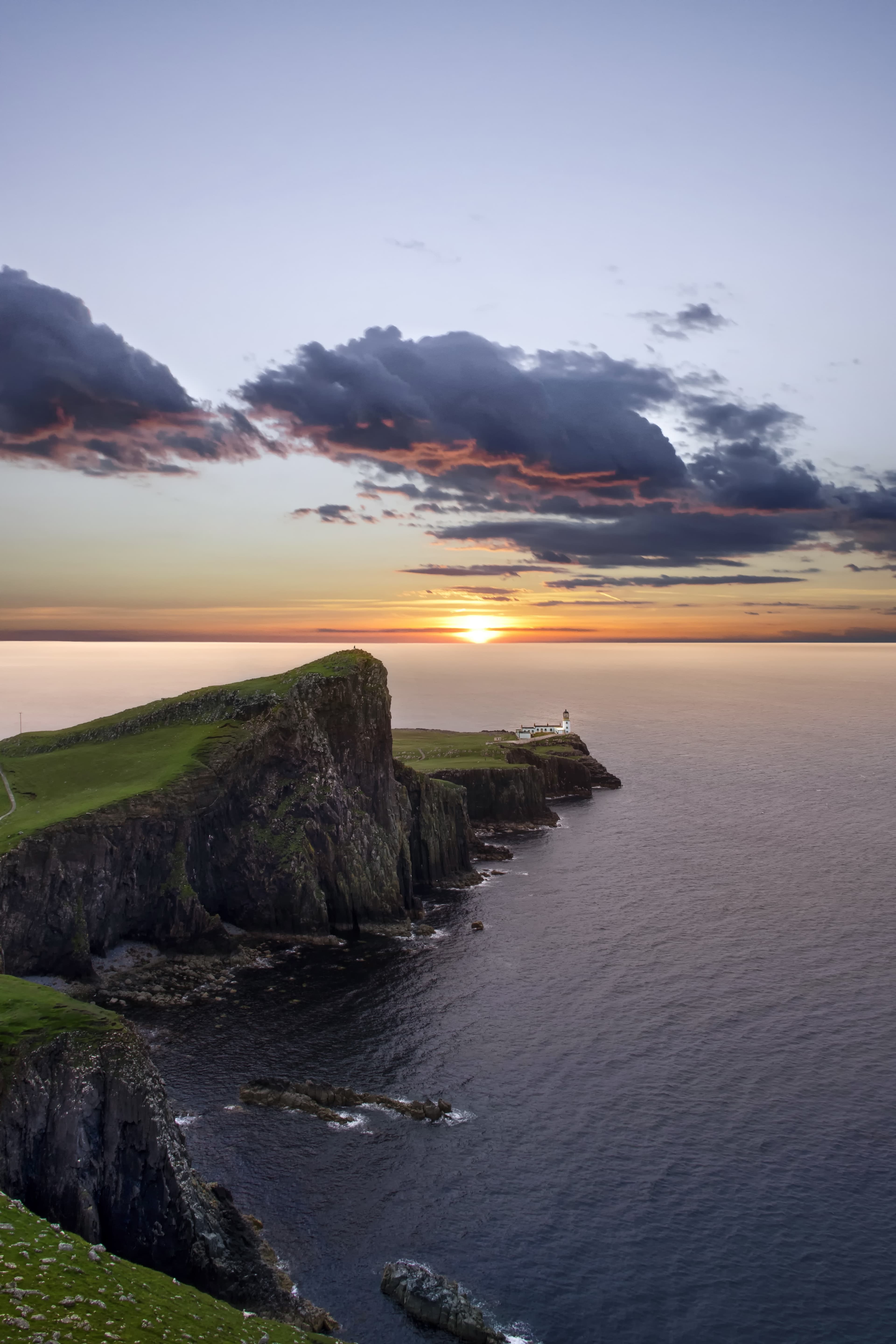 rocky coastline next to body of water during sunset