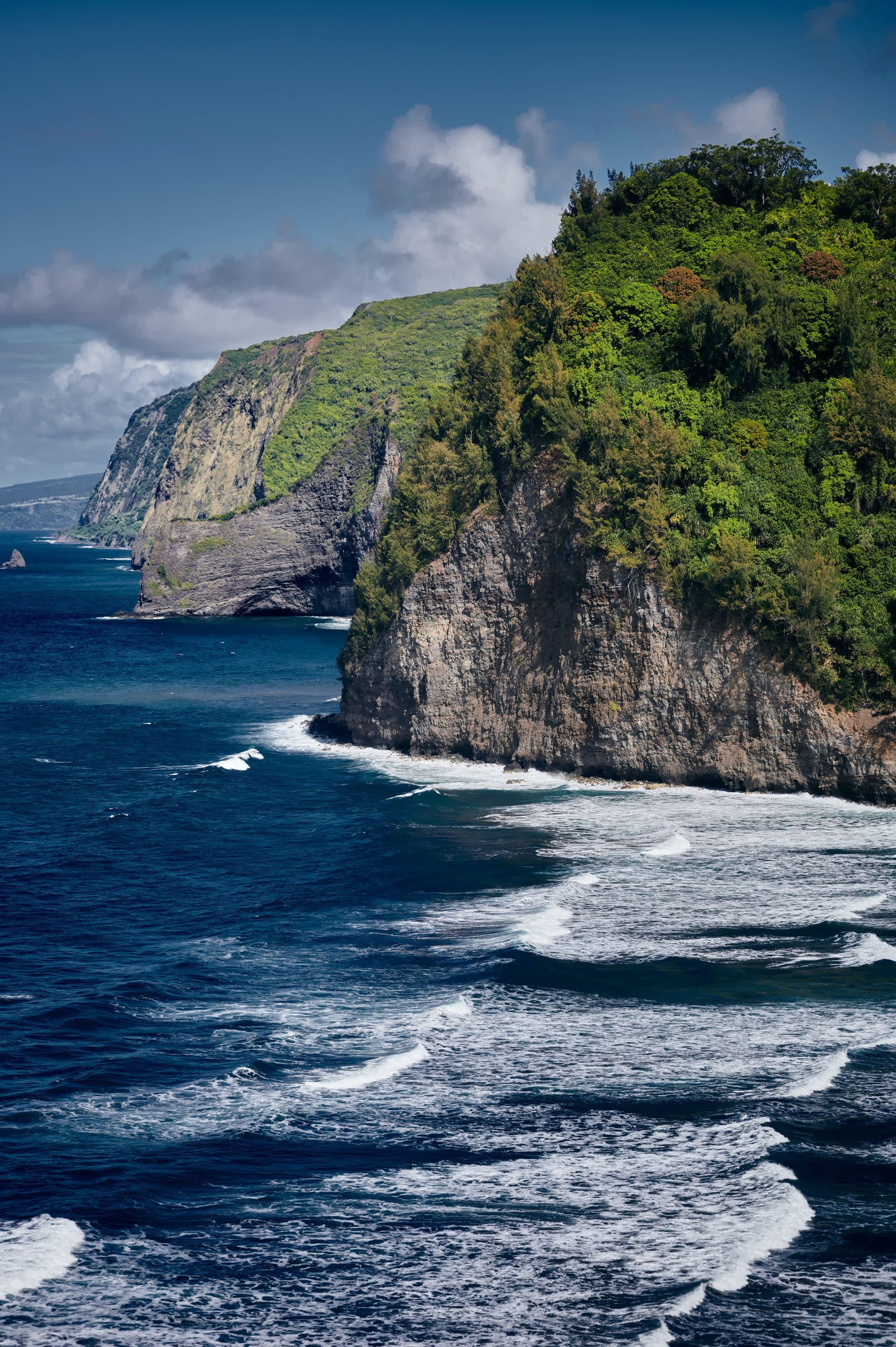 high island cliffs with green tops into deep blue water with white surf