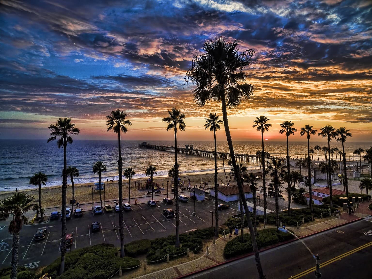 A beautiful view of Oceanside beach with palm trees and a jaw dropping sunset.