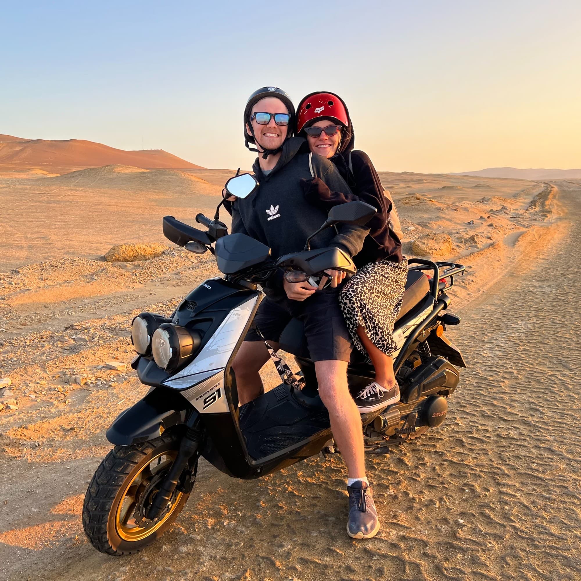A man and woman on a motorcycle in a dessert.
