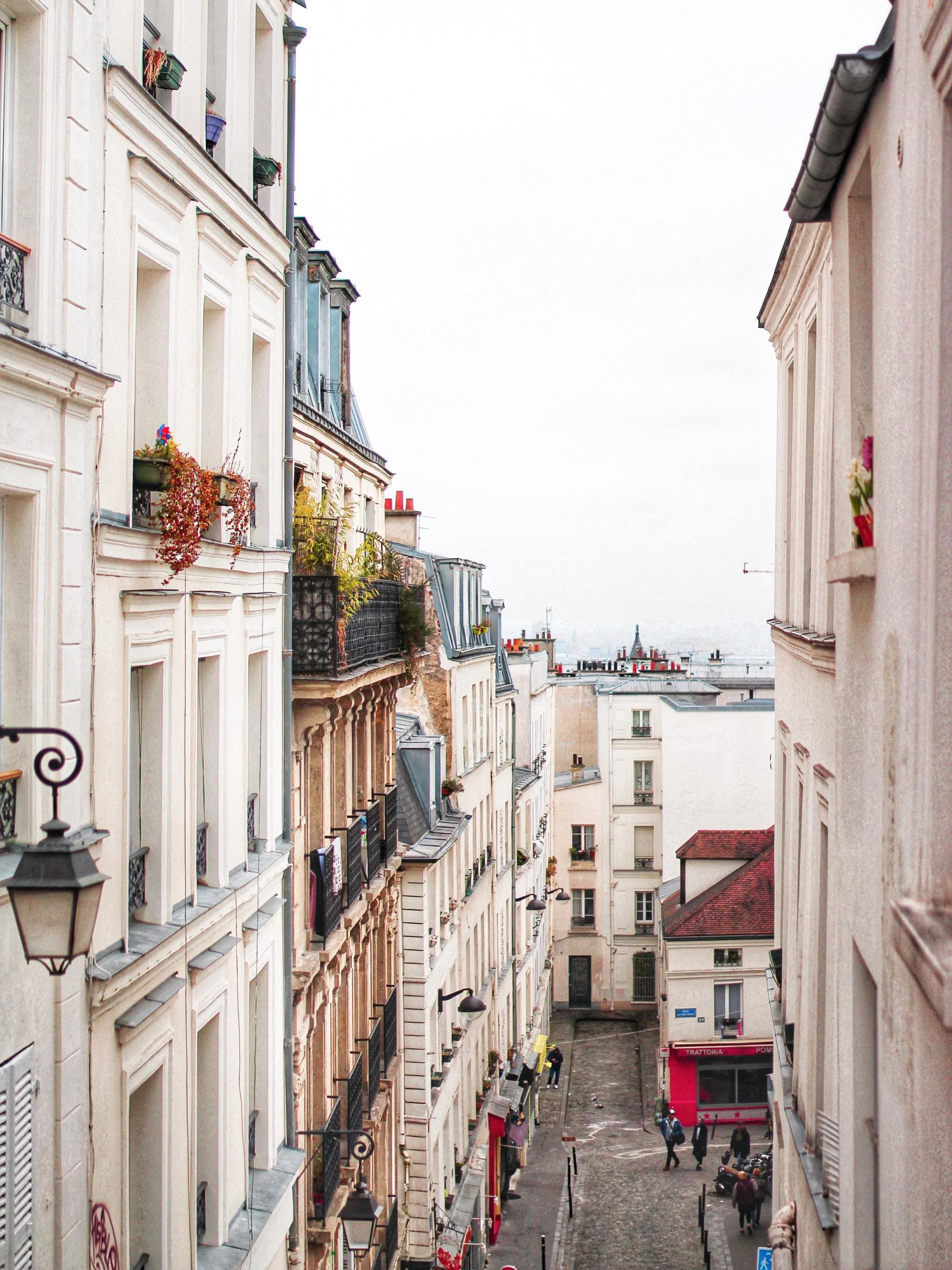looking down hill through a long cobblestone street with white buildings