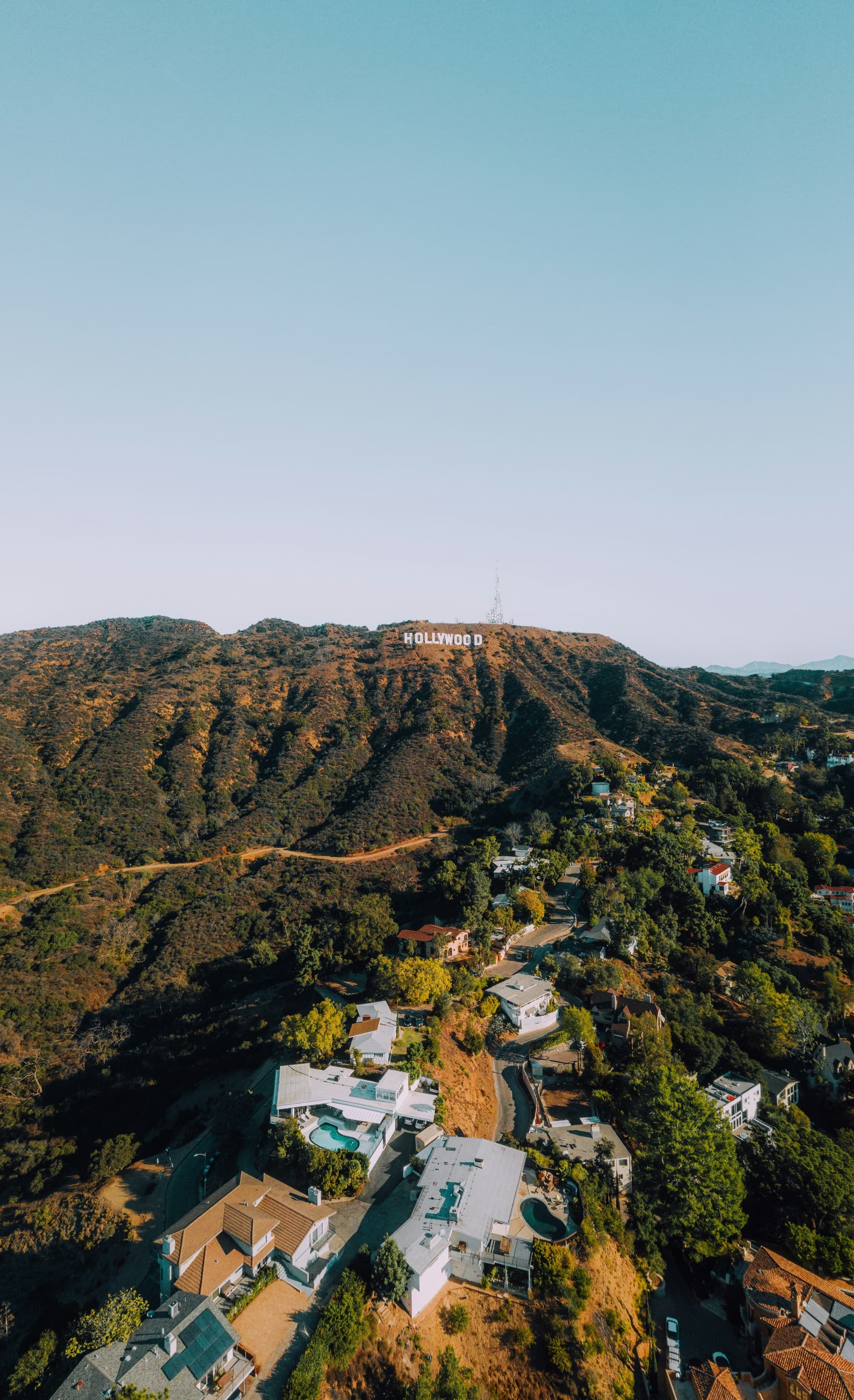 An aerial view of the white houses near green mountains during the daytime.