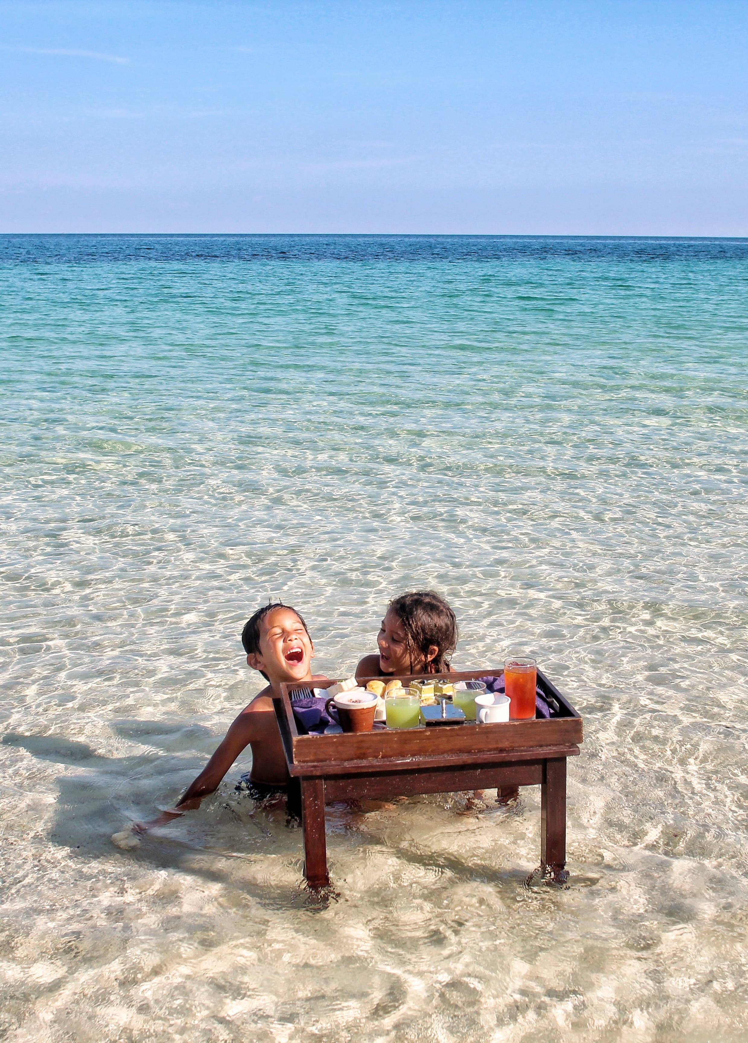 Two girls in the water on a transparent beach.