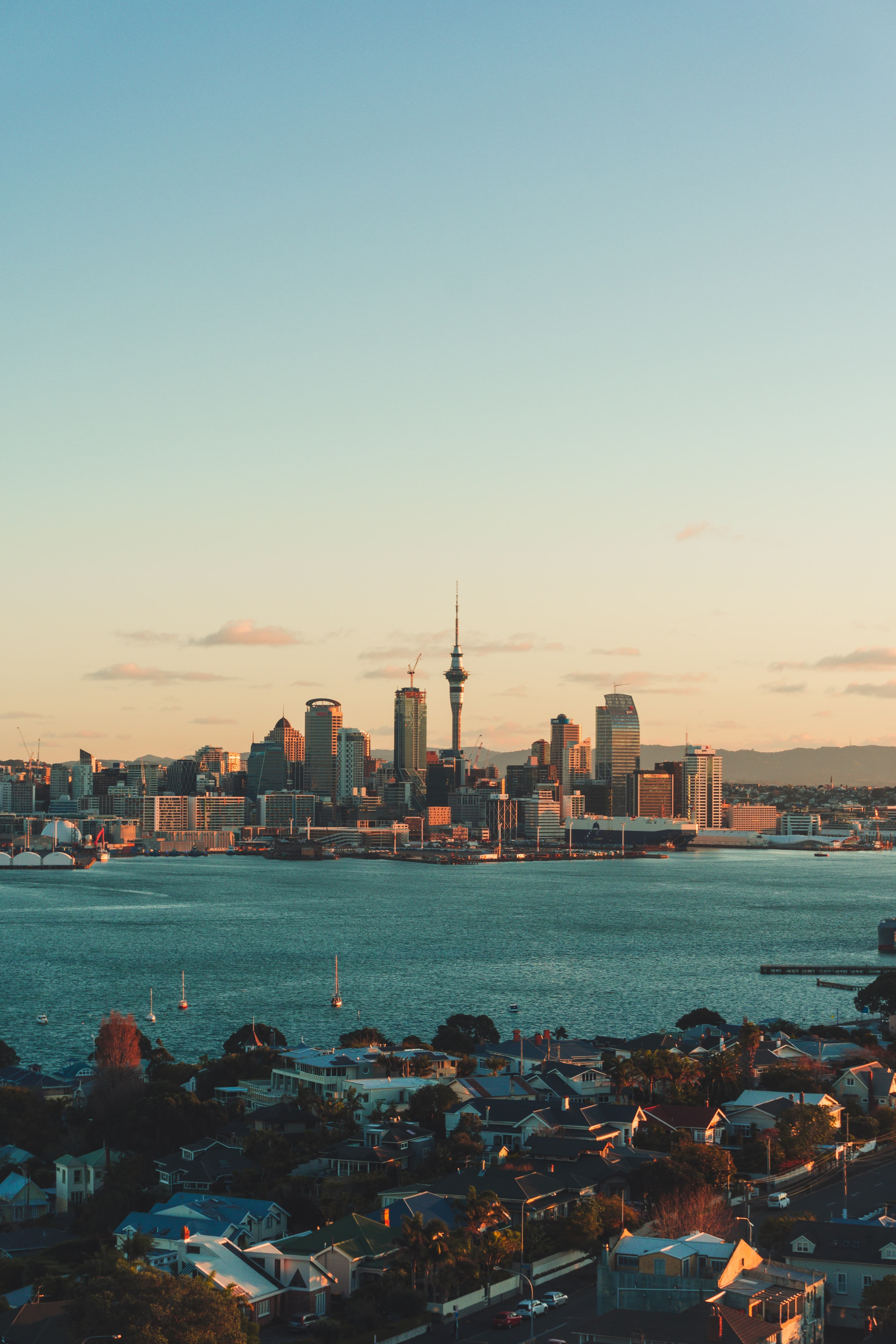 A city view of Auckland, New Zealand at sunset overlooking a blue lake.
