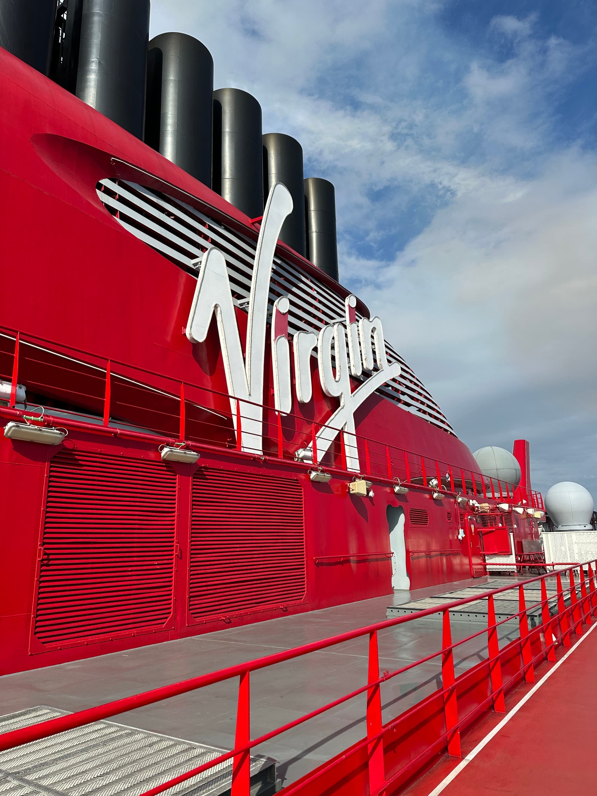 A sign of placed on a red colored cruise ship saying "Virgin".