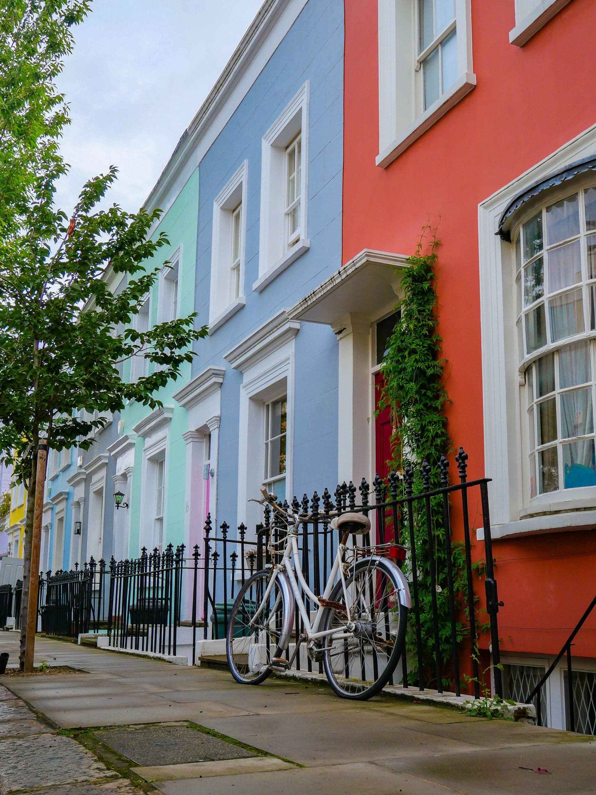 pastel and bright colored houses and a bicycle leans on the wrought iron fence