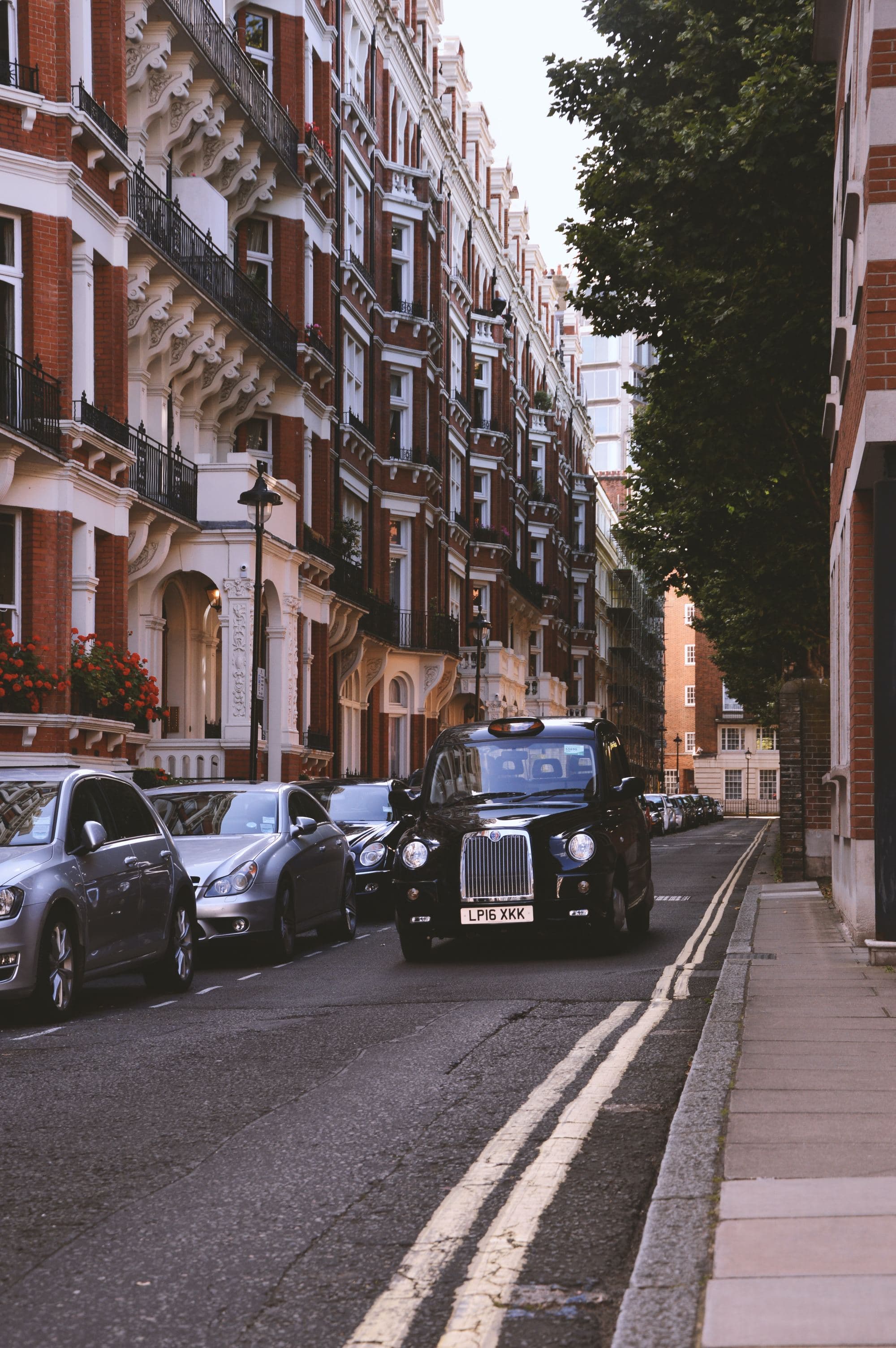 black cab drives down street with brick buildings