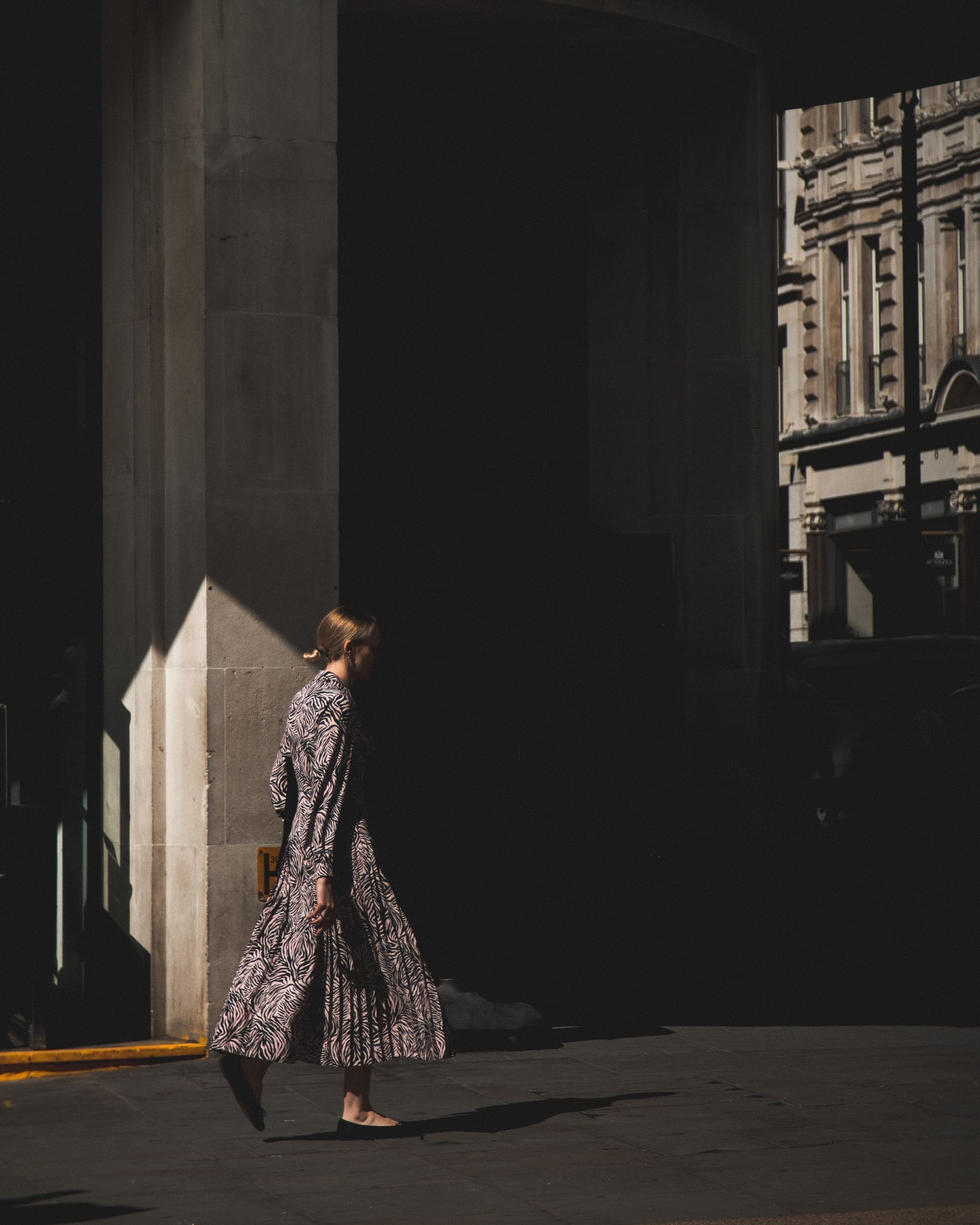 Woman in purple and white dress walking.
