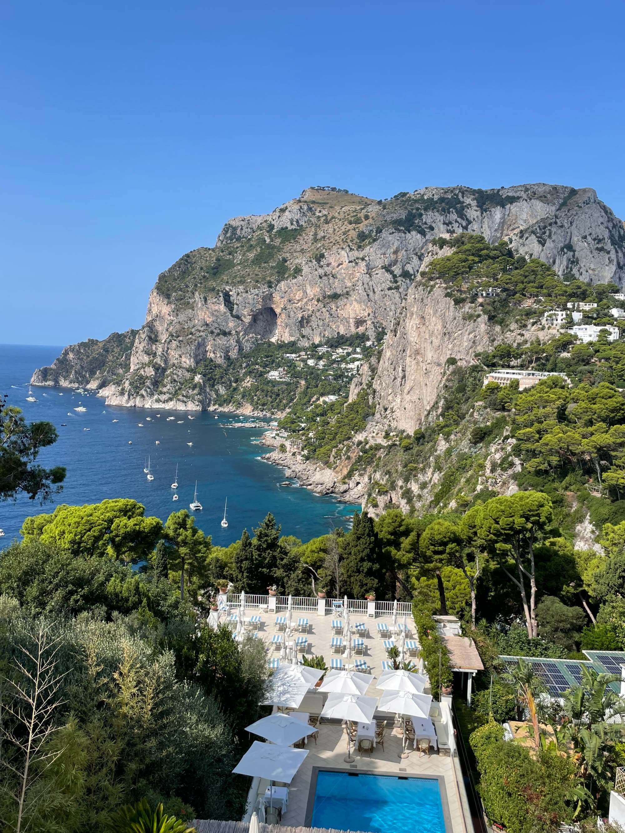 Aerial view of a resort, mountains and ocean with boats.