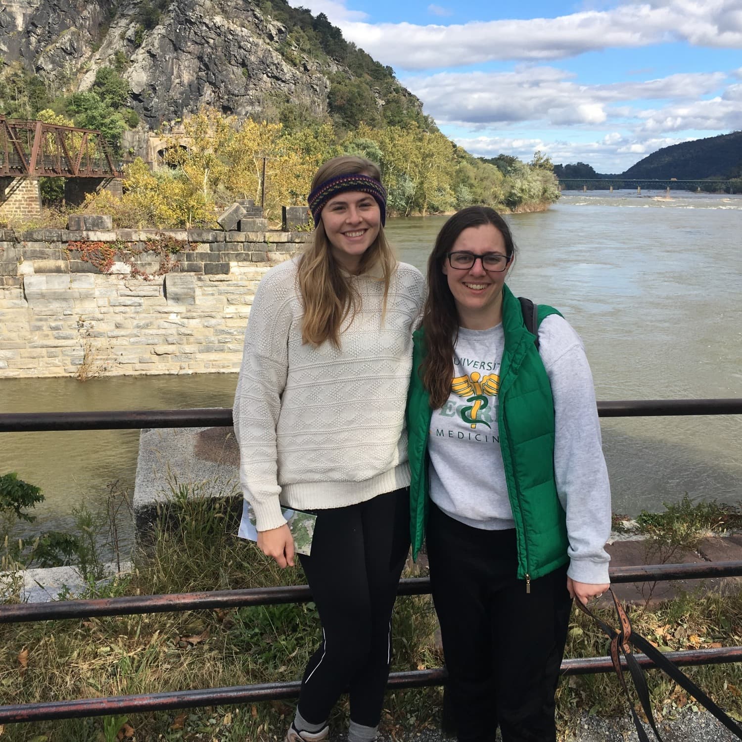 Two women in front of a lake surrounded by rocky hills.