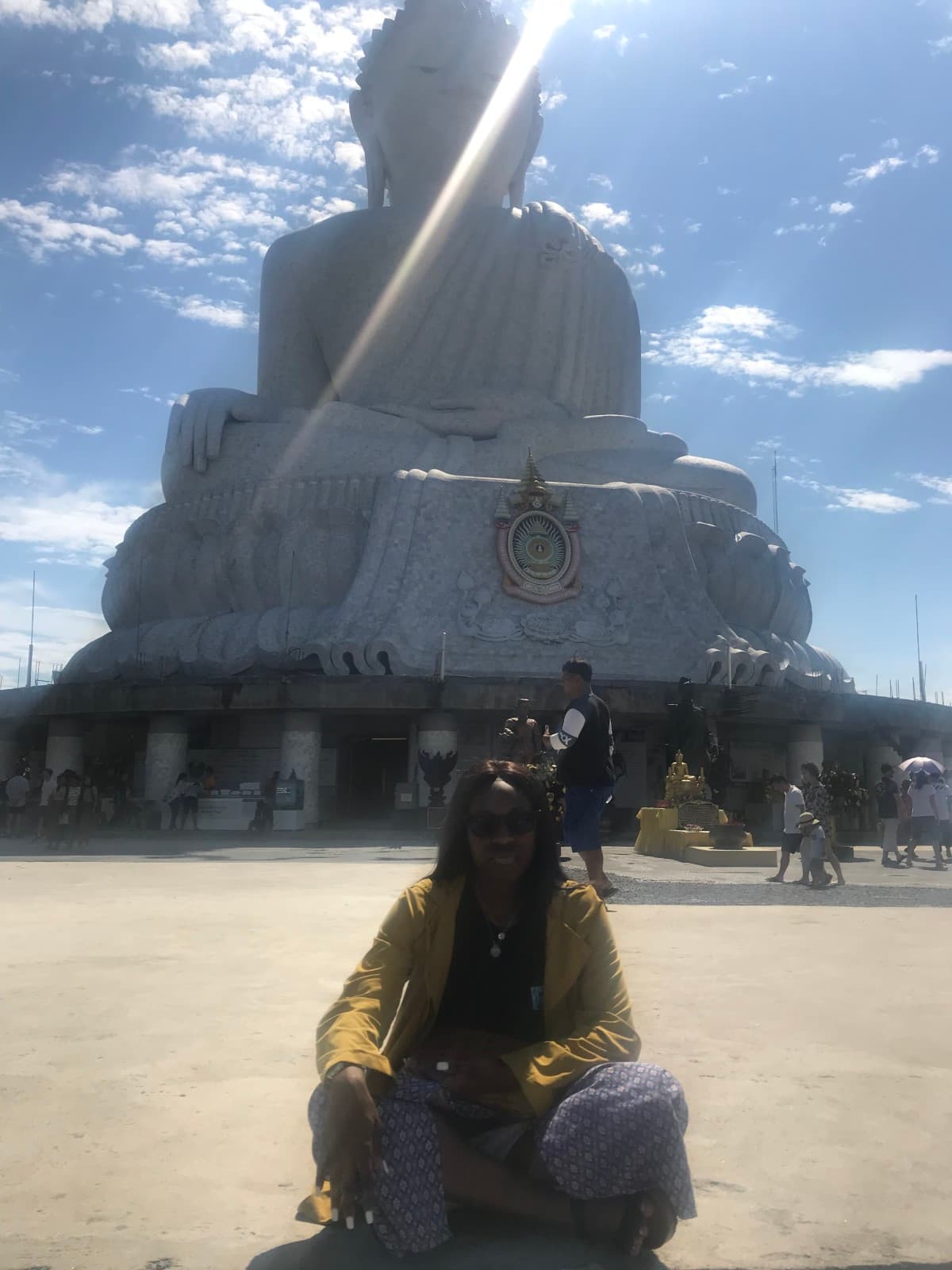 Person sitting in front of a large, white Buddha statue