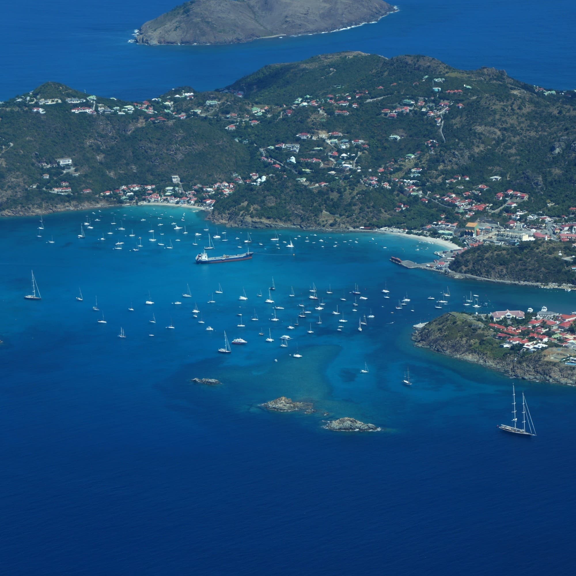 An aerial view of a small island with boat in the water.