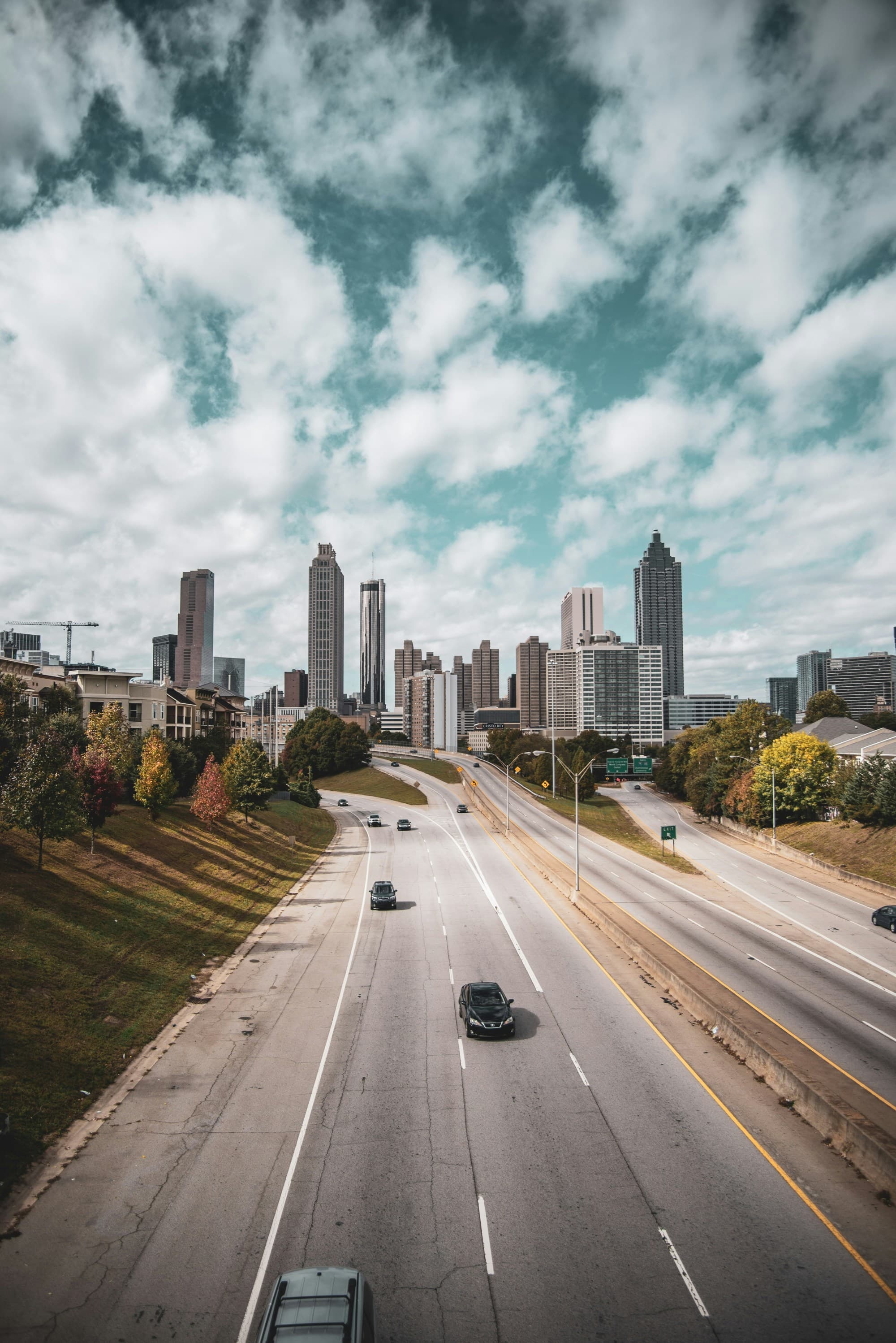 Road with cars going towards city buildings.