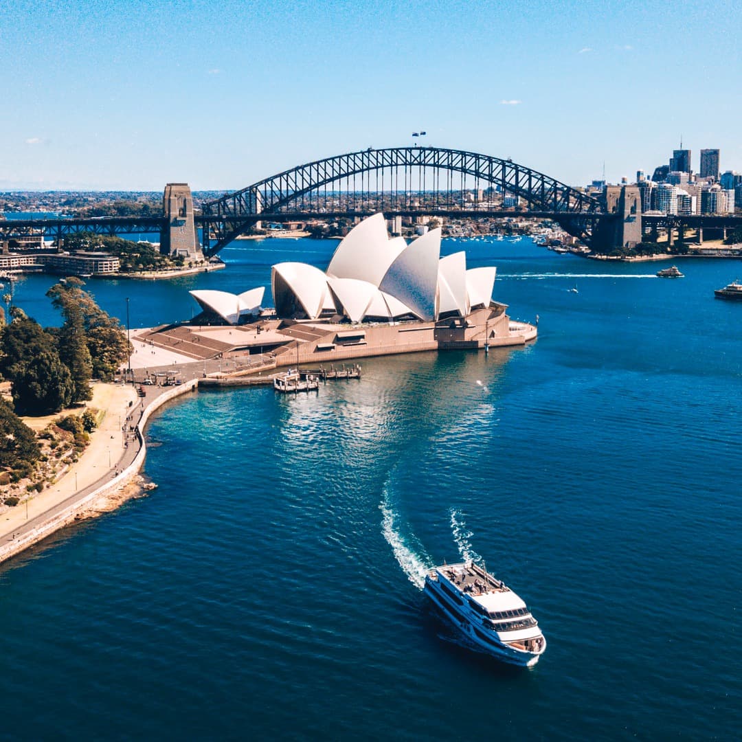 Bird's eye view of the city from the water overlooking the opera house on a sunny day.