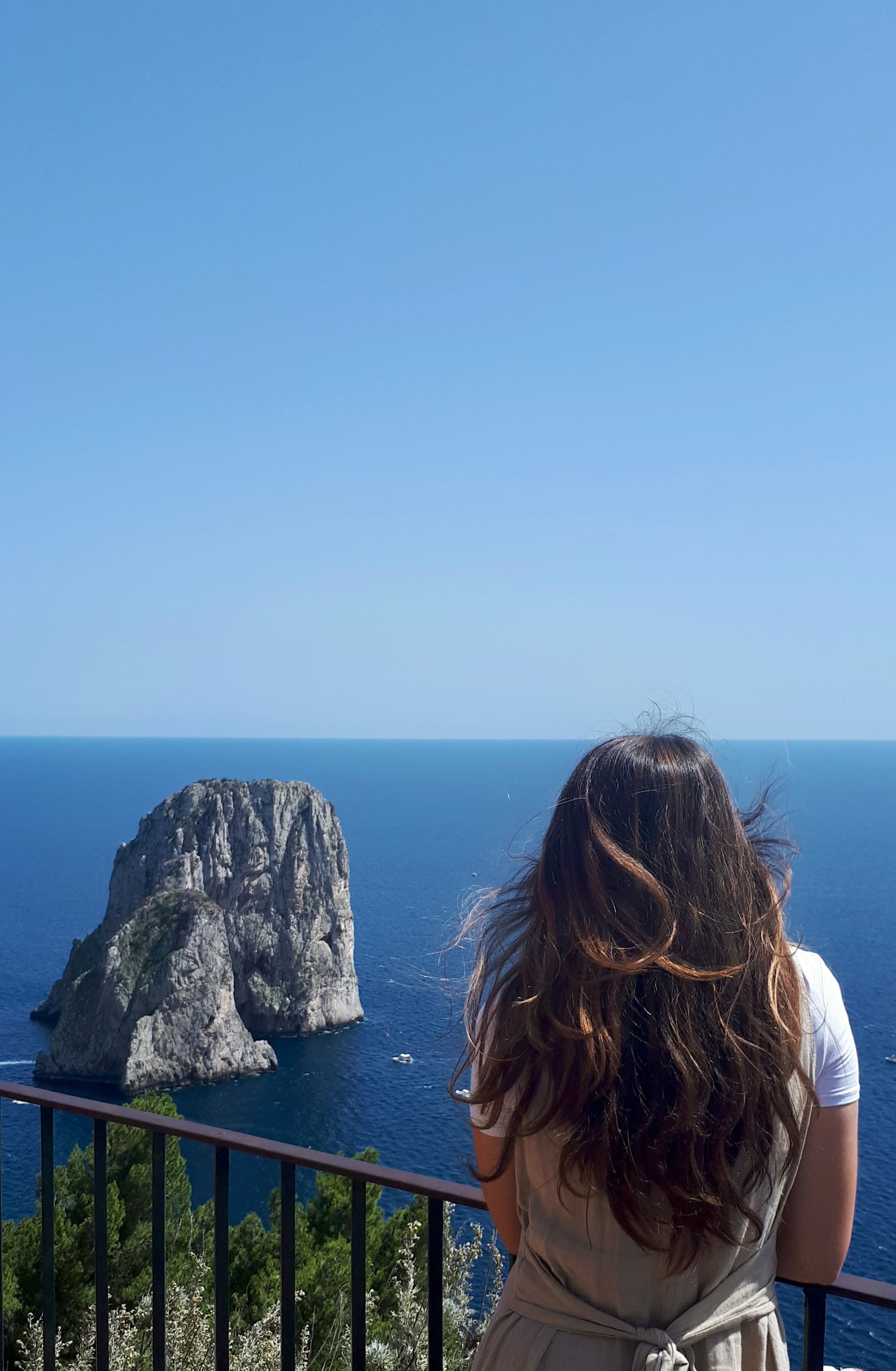 Girl standing in front of sea and rock.