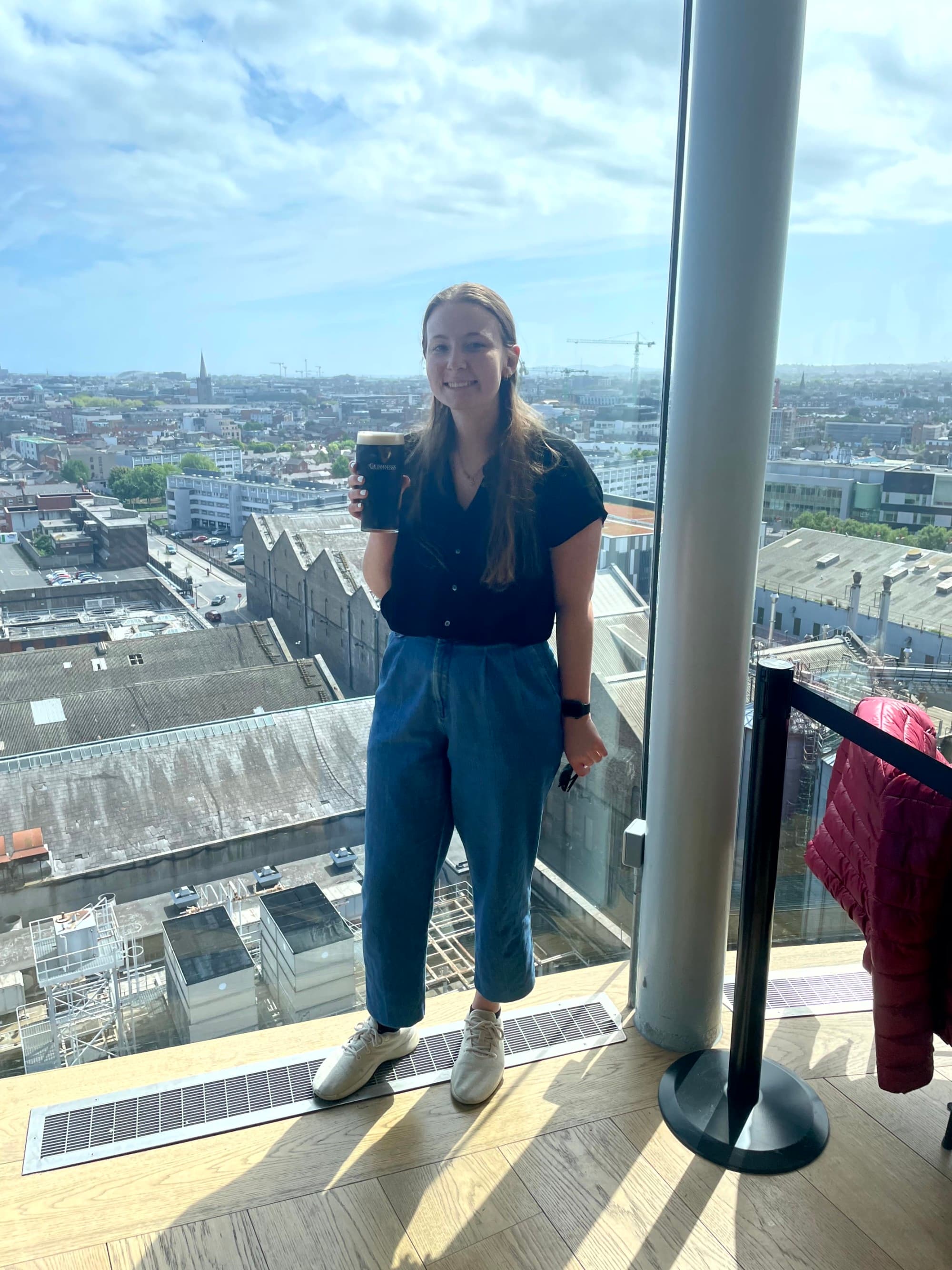 A girl posing at the Guinness Storehouse Roof holding a glass of drink.