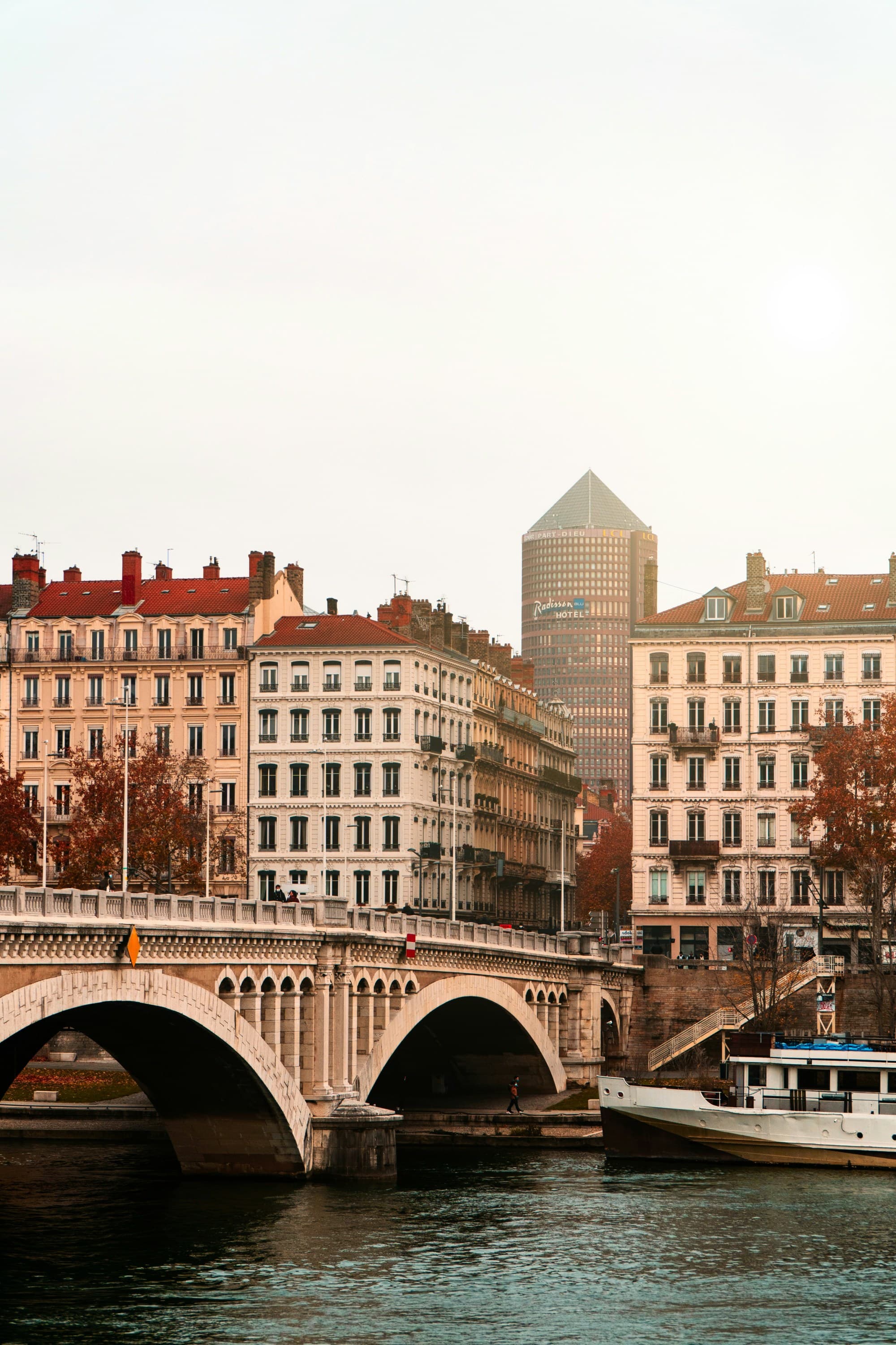 A picturesque cityscape with a bridge, traditional buildings and a modern skyscraper in the background.