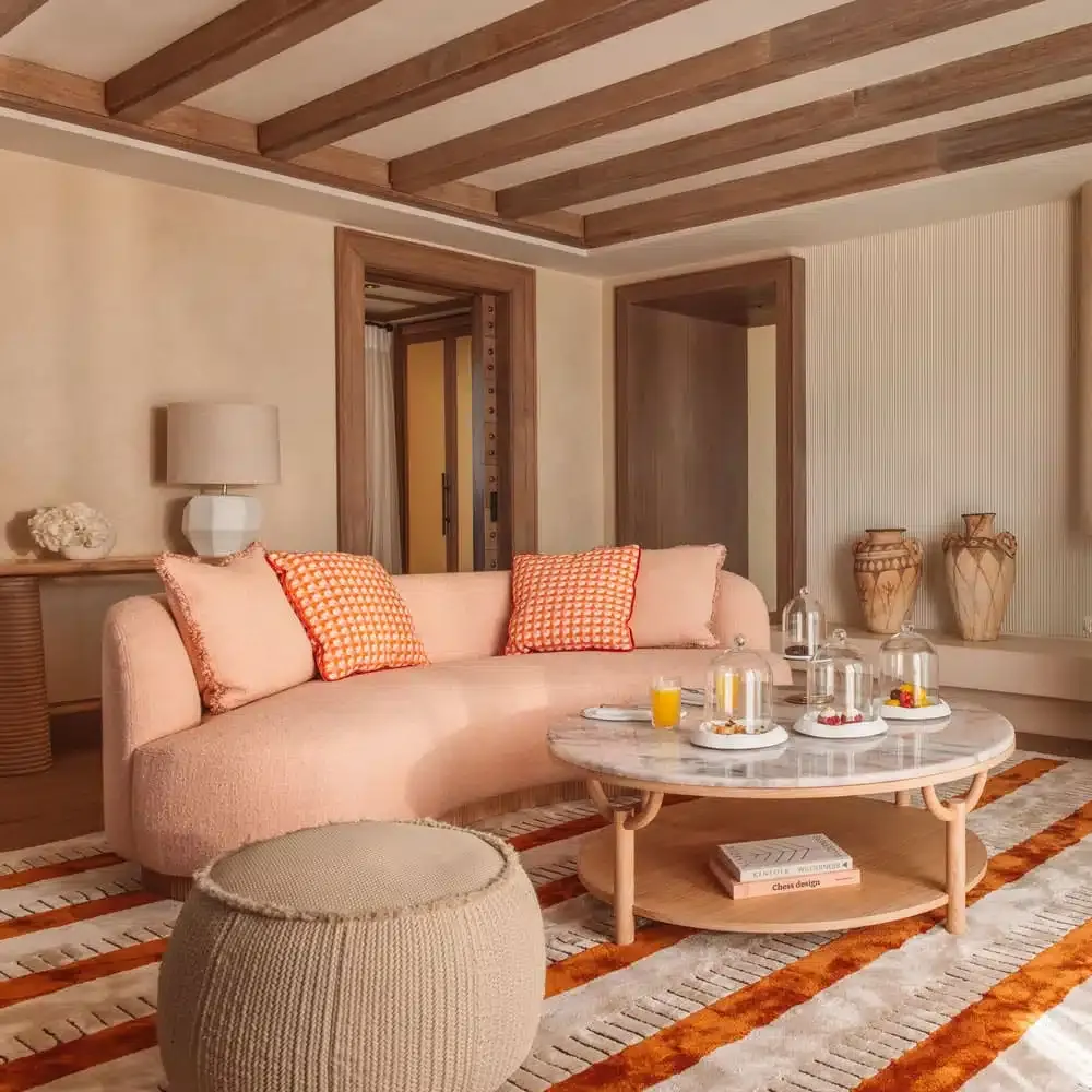a hotel room decorated with pastel pink furniture and a striped rug