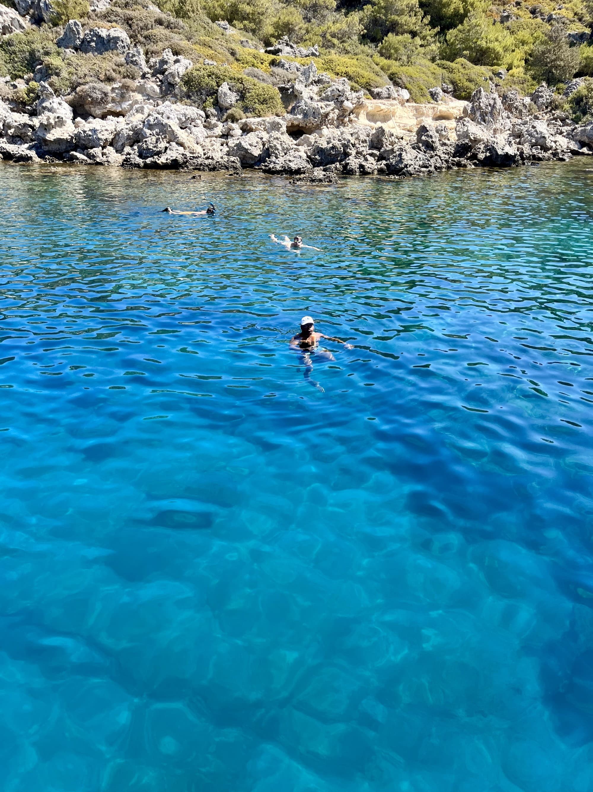 A view of people swimming in bright blue waters in Rhodes Cove.