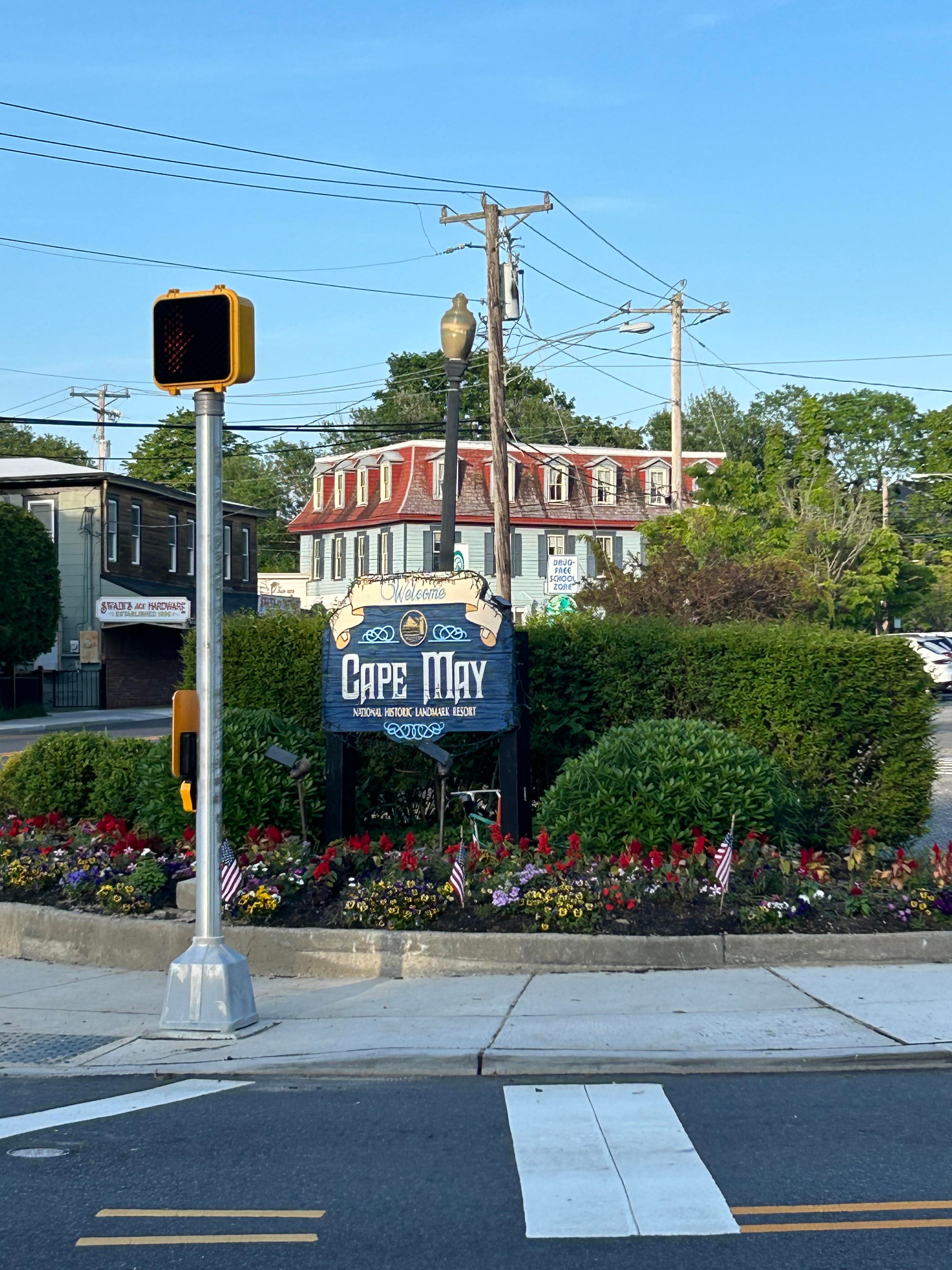 Welcome signage at Cape May on a sunny day surrounded by foliage.