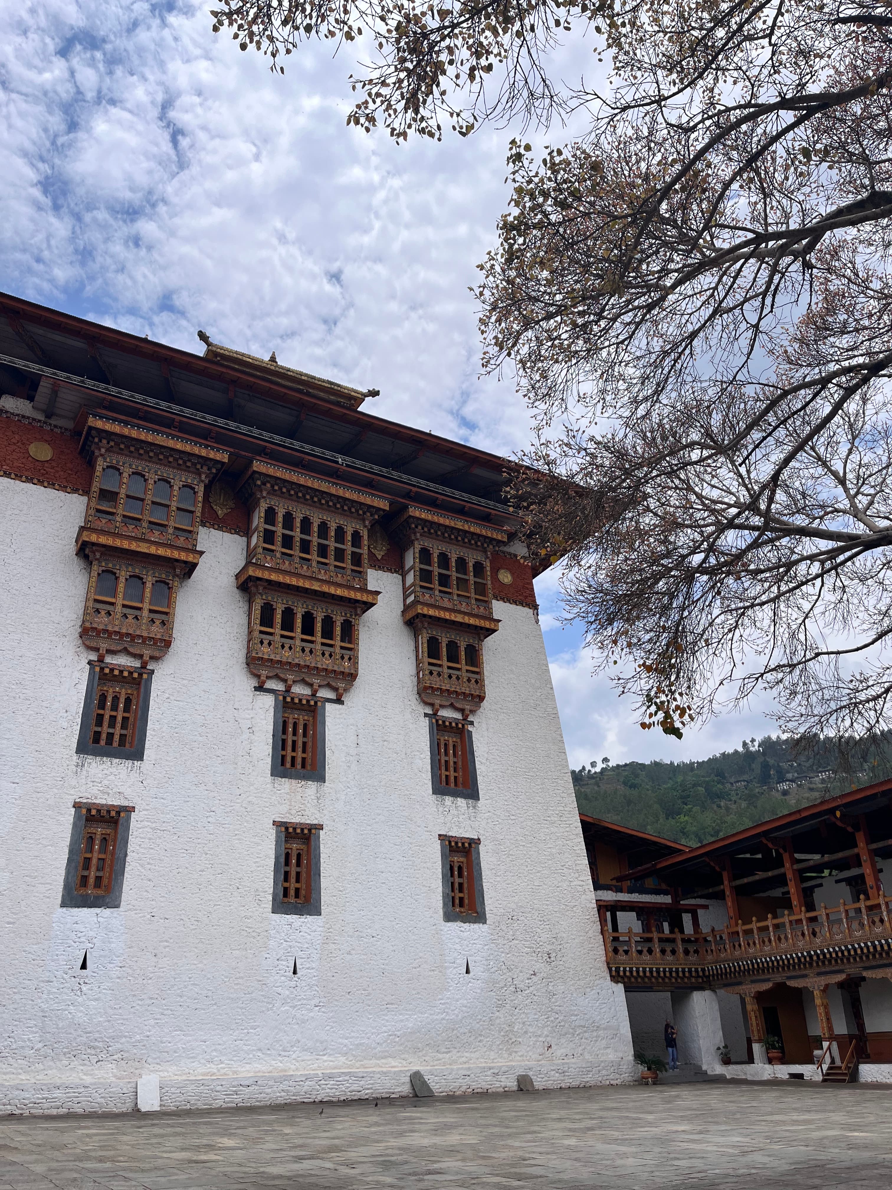 A large white building with traditional wooden architectural features and a cloudy sky backdrop.