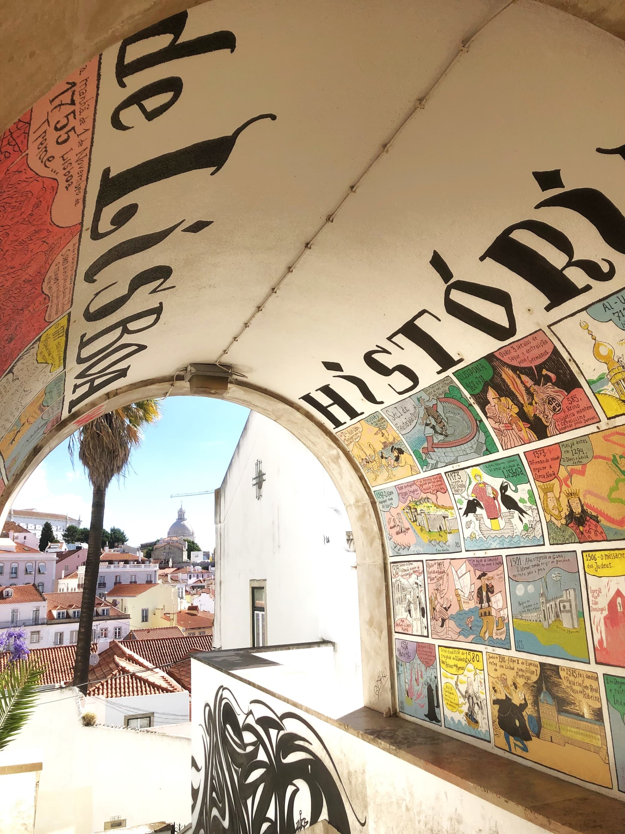 A vibrant mural under an archway with the word “History,” overlooking a sunny cityscape.
