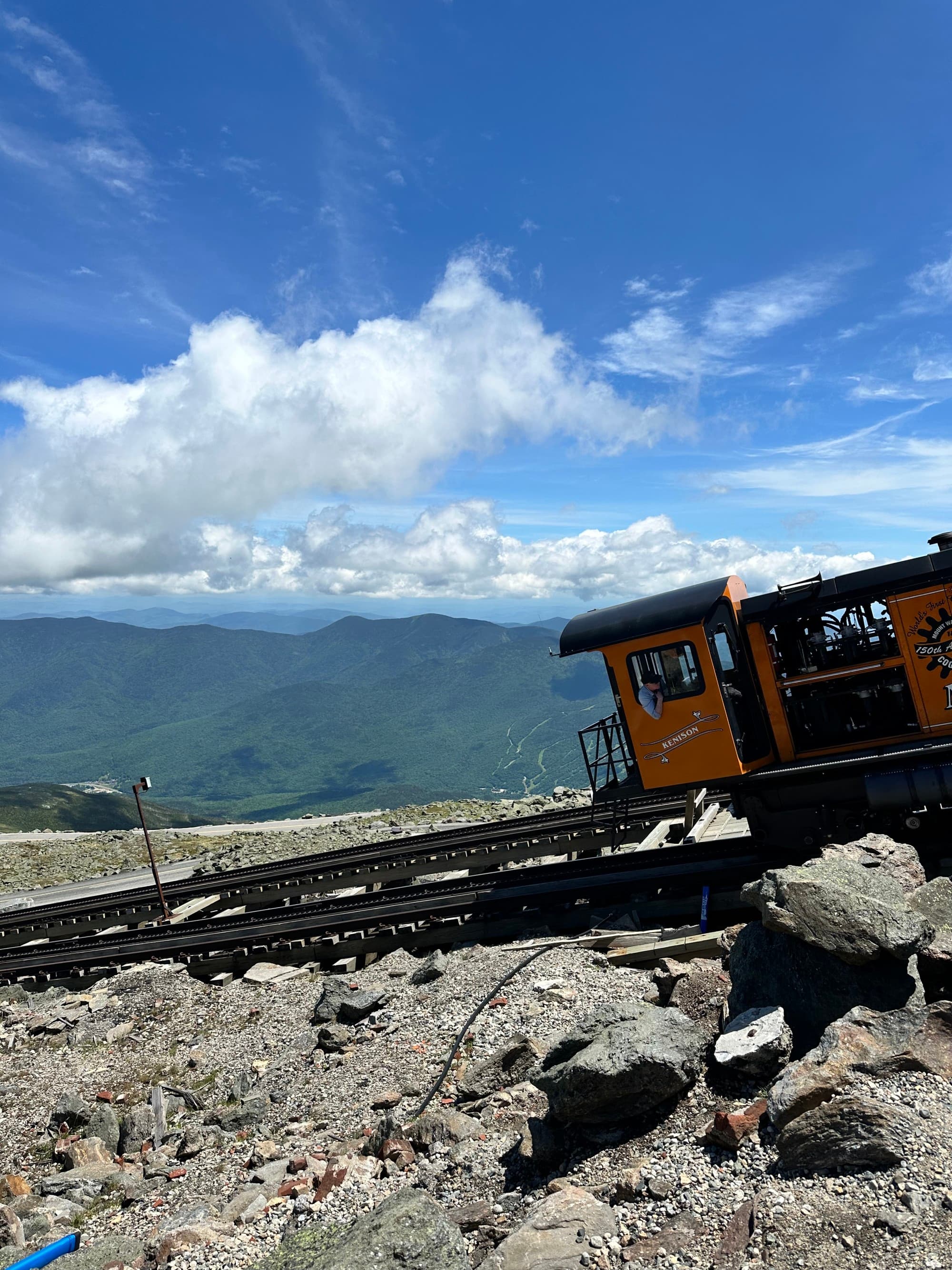A cogwheel train ascending a mountain track under a clear blue sky.
