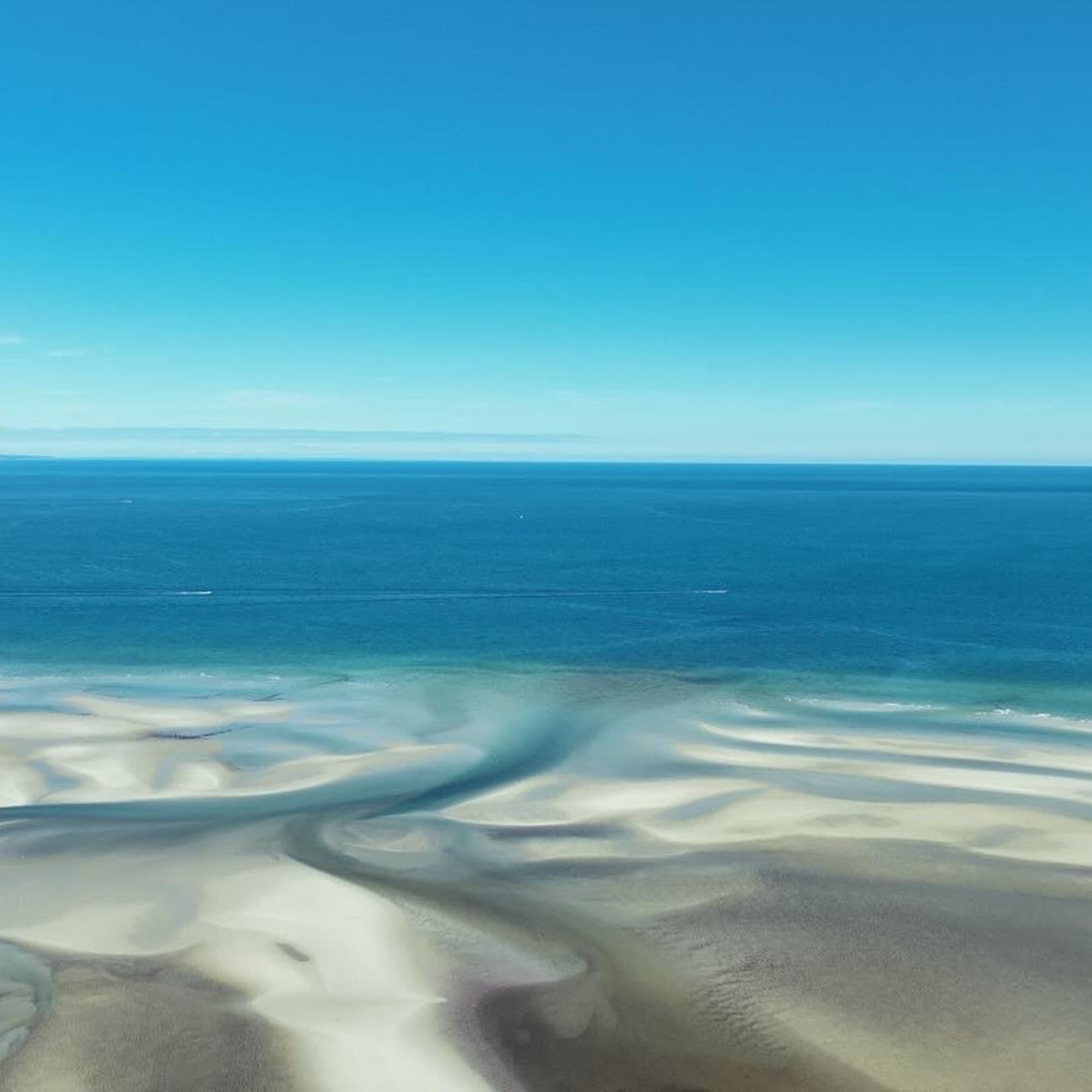 A serene coastal landscape with intricate patterns formed by sand and water channels.