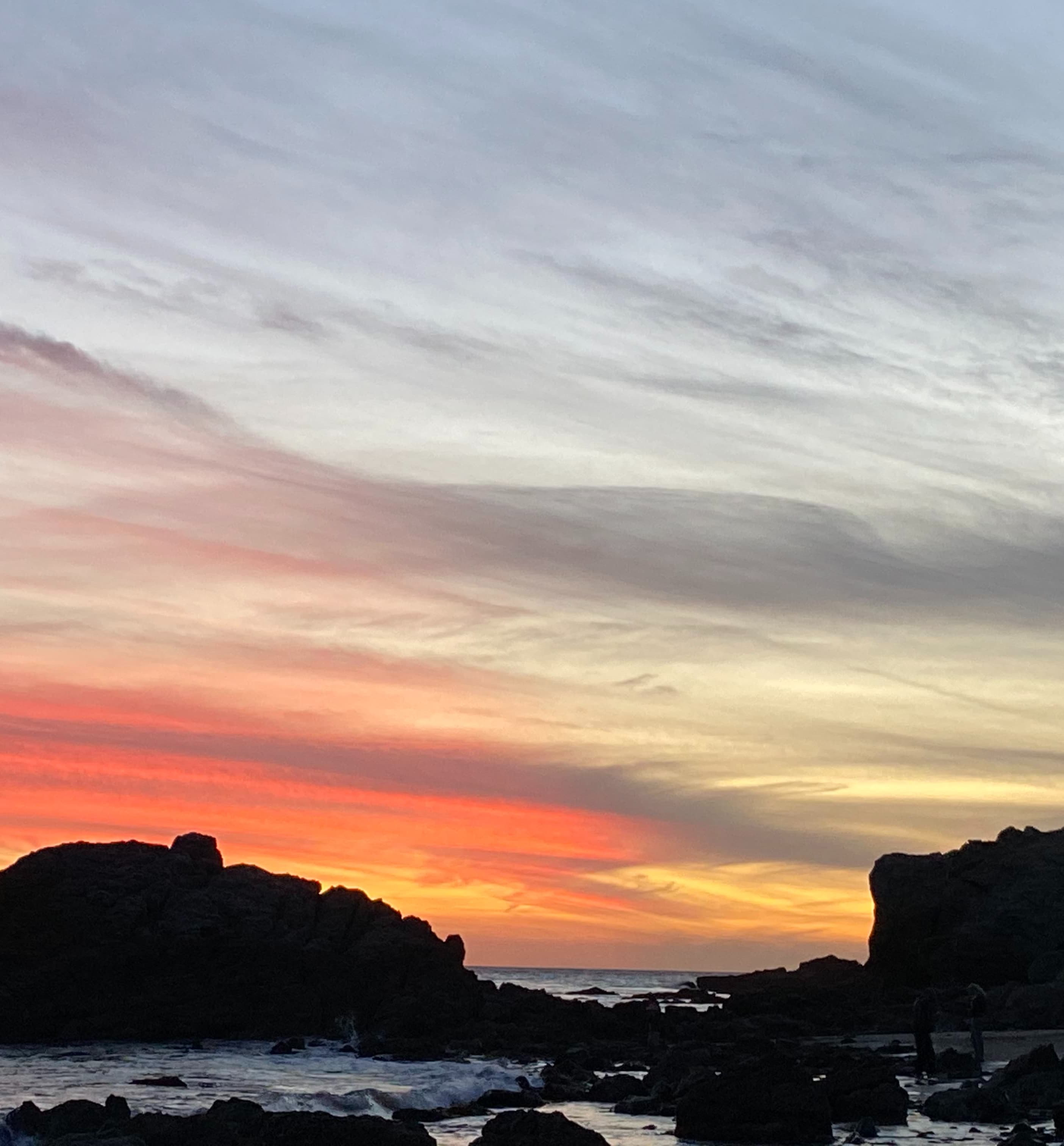 Leo Carrillo Beach, a rocky beach at sunset with the sky illuminated yellow and orange.