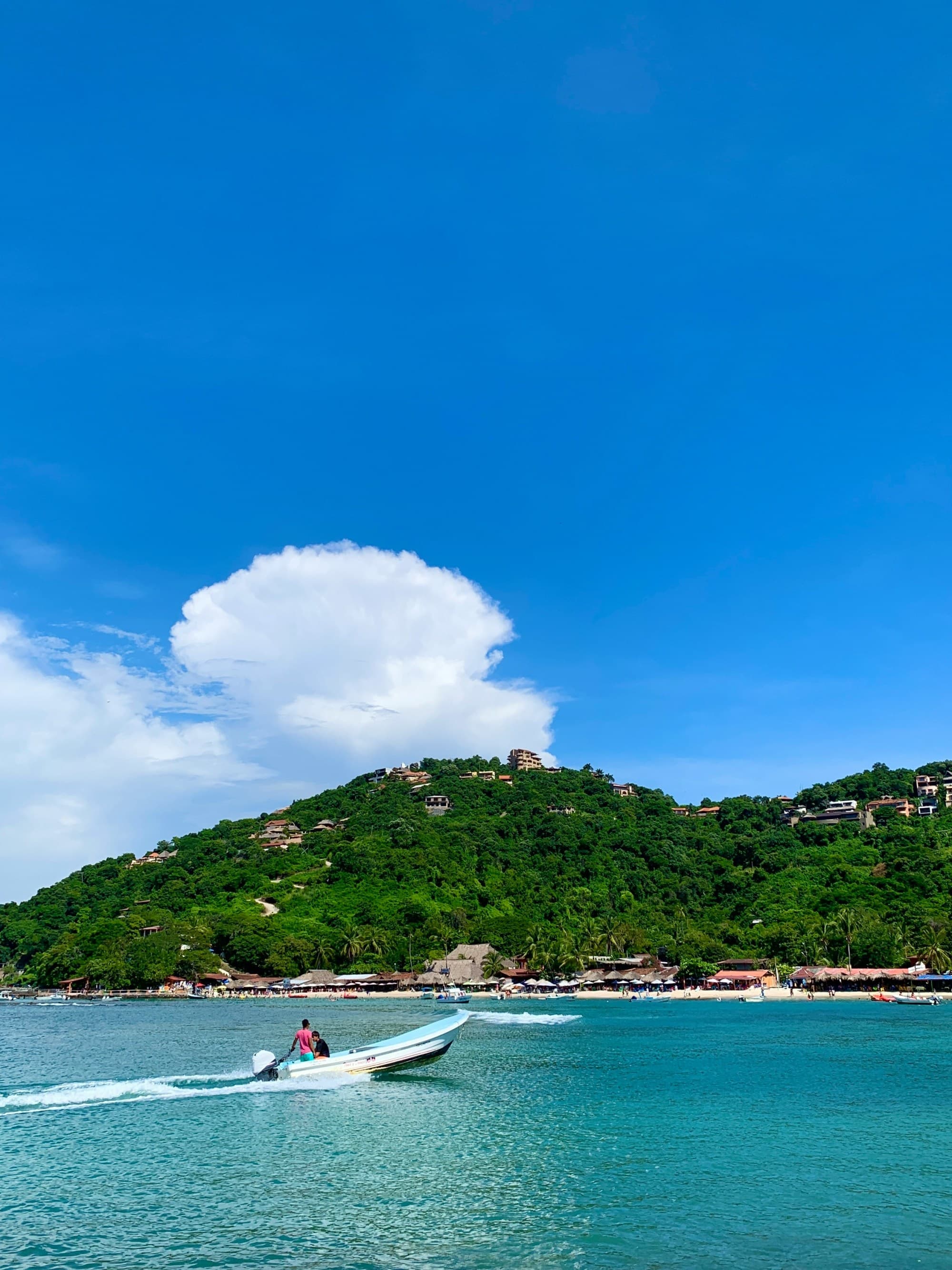 Boats on the water with a forest-covered hill in the distance