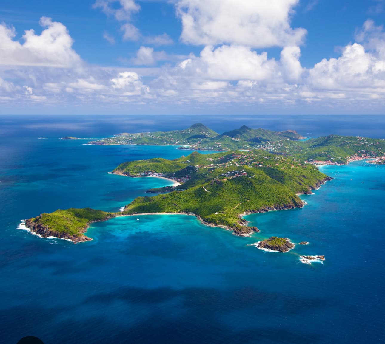 Aerial view of grey landscape with a green body of water and greenery