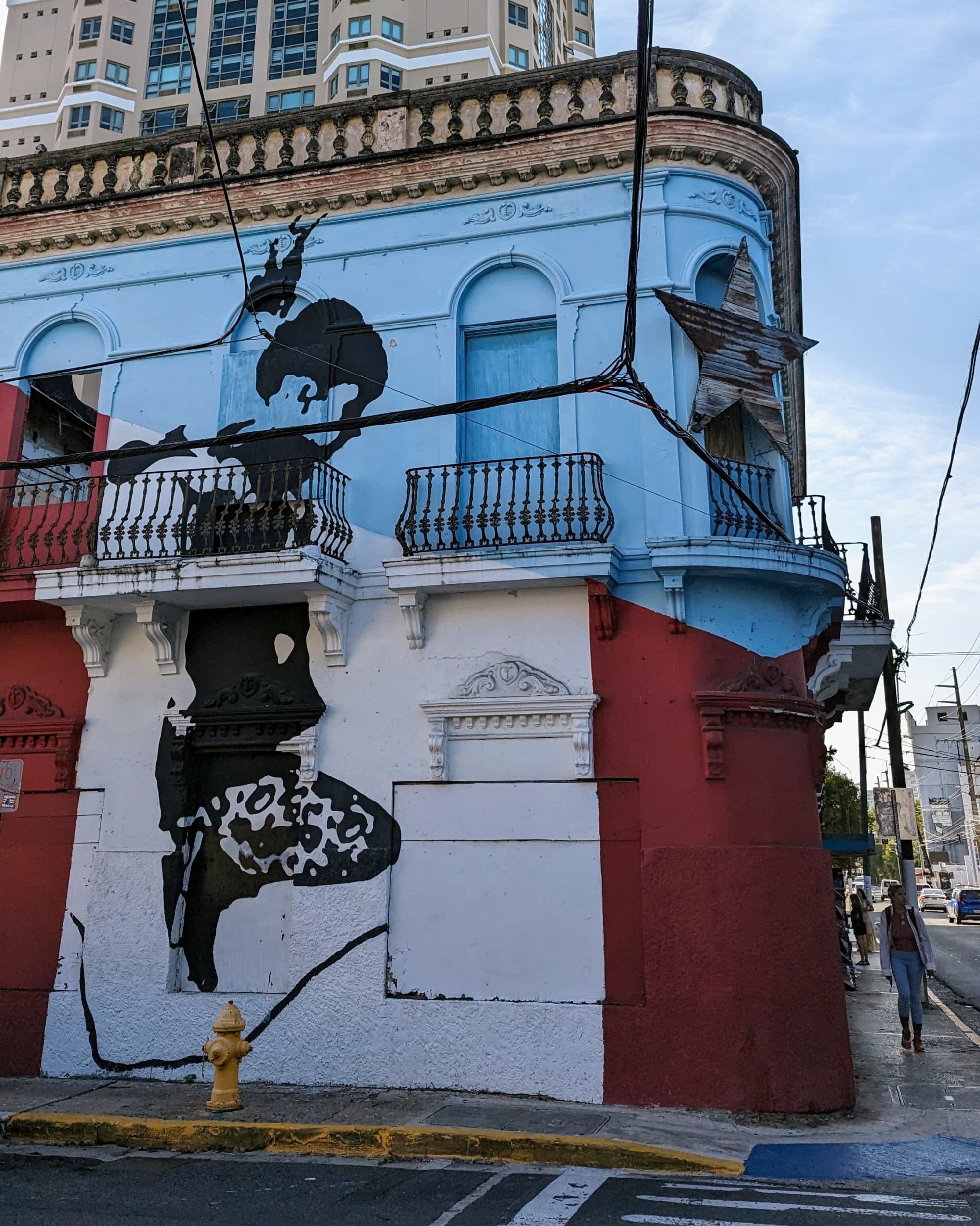 A striking street corner mural of a black and white figure, adding artistic character to the urban landscape.