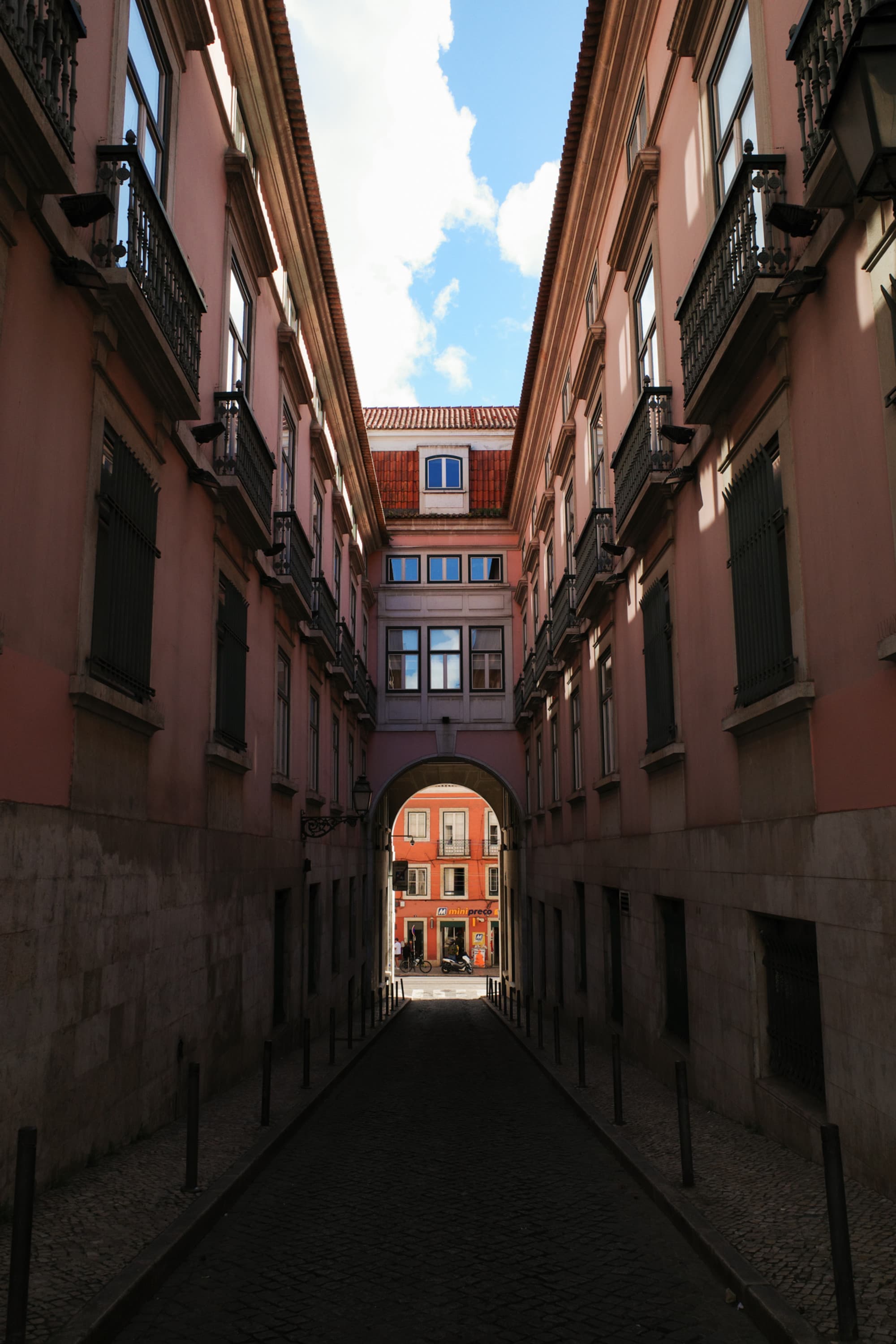 The image depicts a picturesque cobblestone street lined with traditional European buildings under a clear sky.