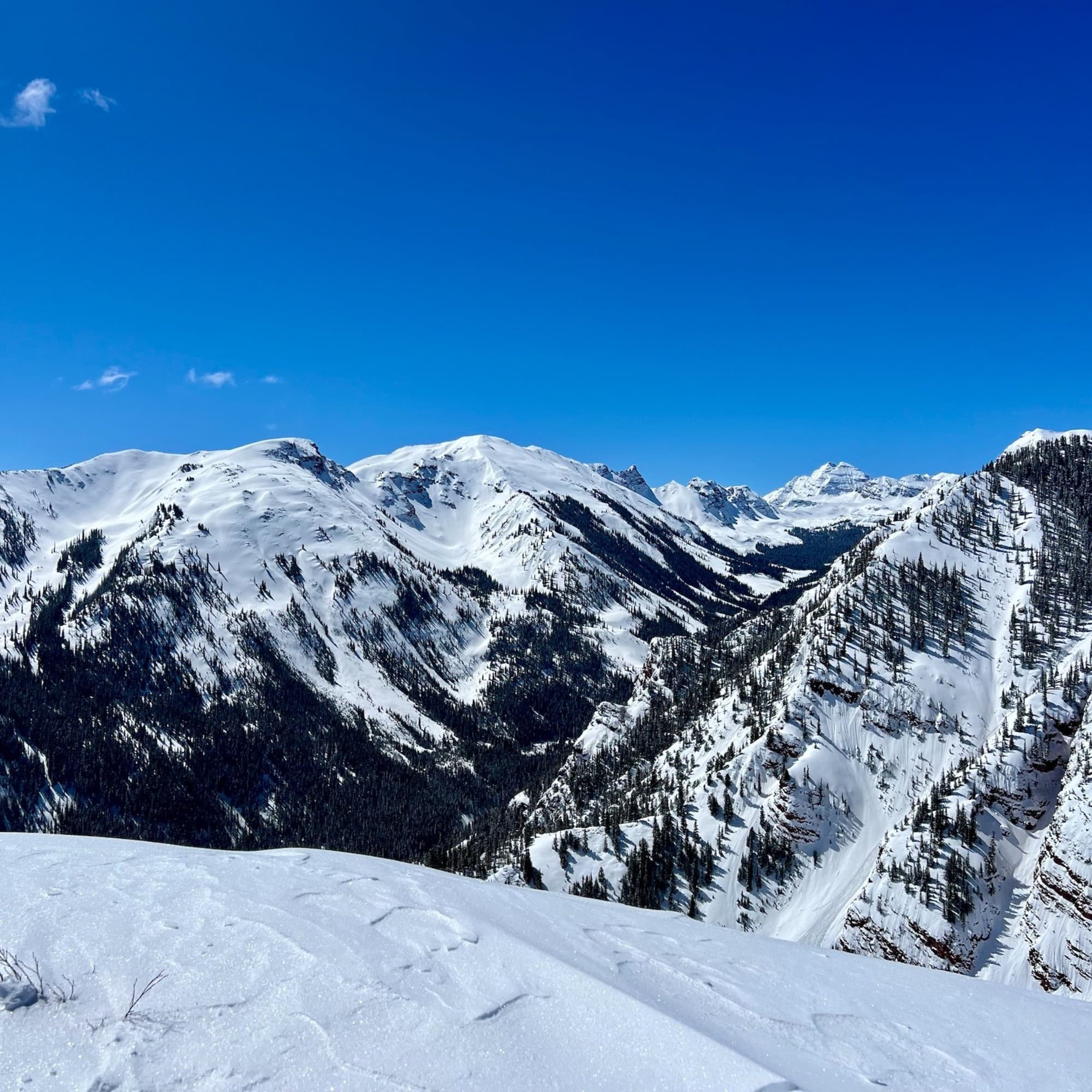 The image depicts a pristine snow-covered mountain landscape under a clear blue sky.