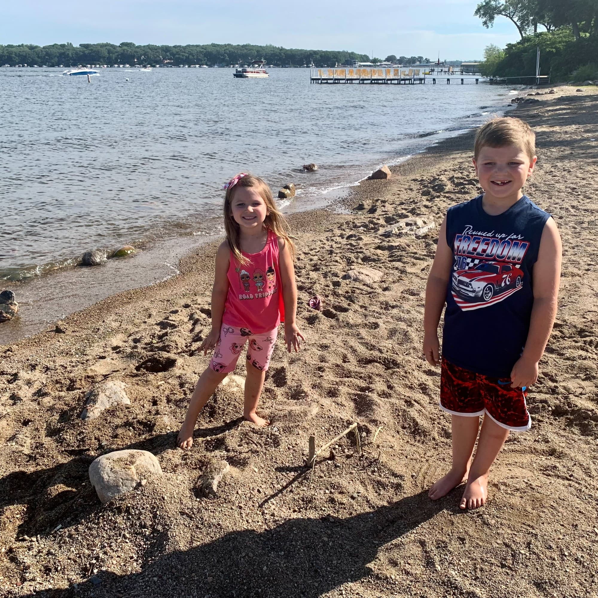 Two children on a beach next to the water during the daytime