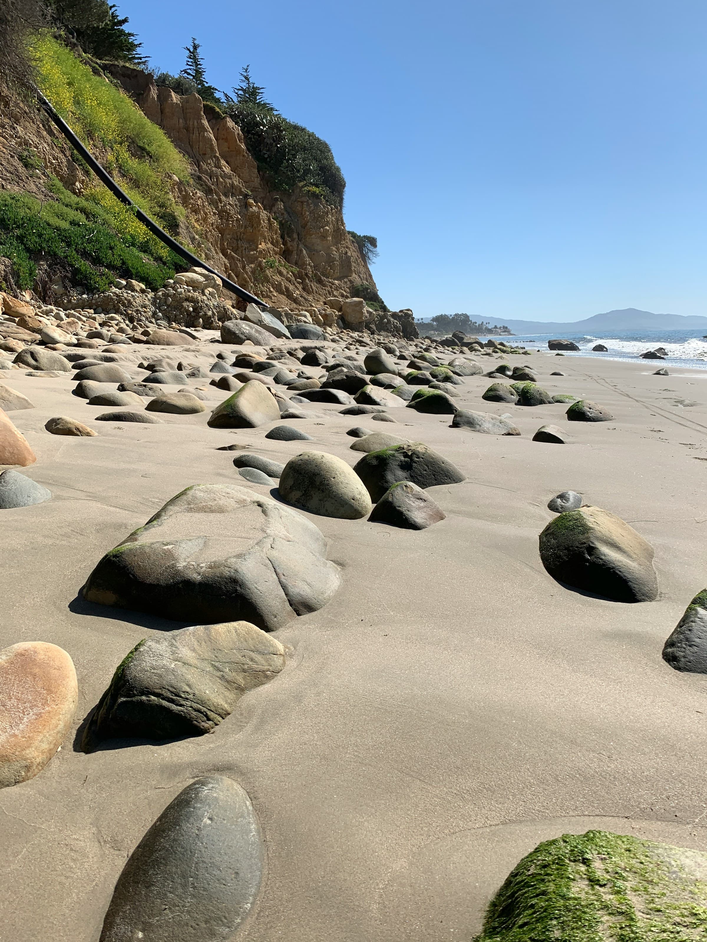 A sandy beach with large rocks scattered around