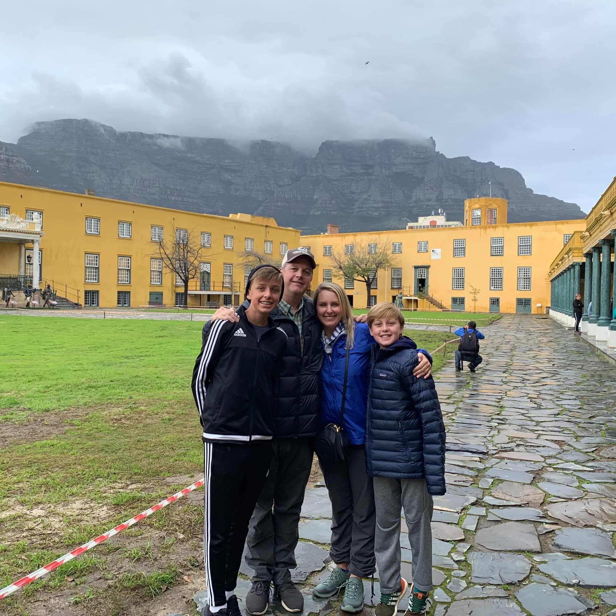 A family in front of a yellow building with mountains in the distance