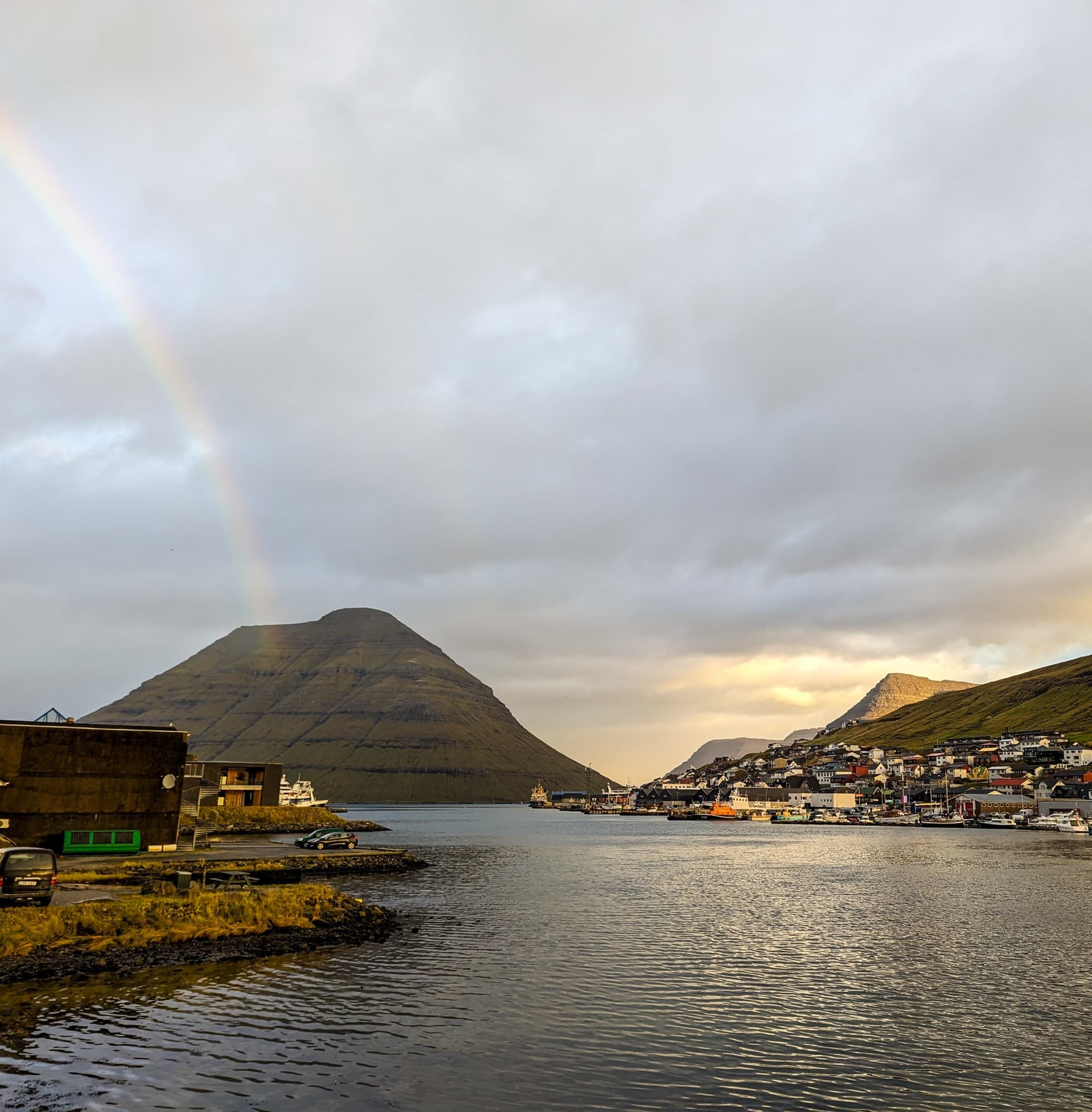 View of a river with a mountain in the background and rainbow in the cloudy sky