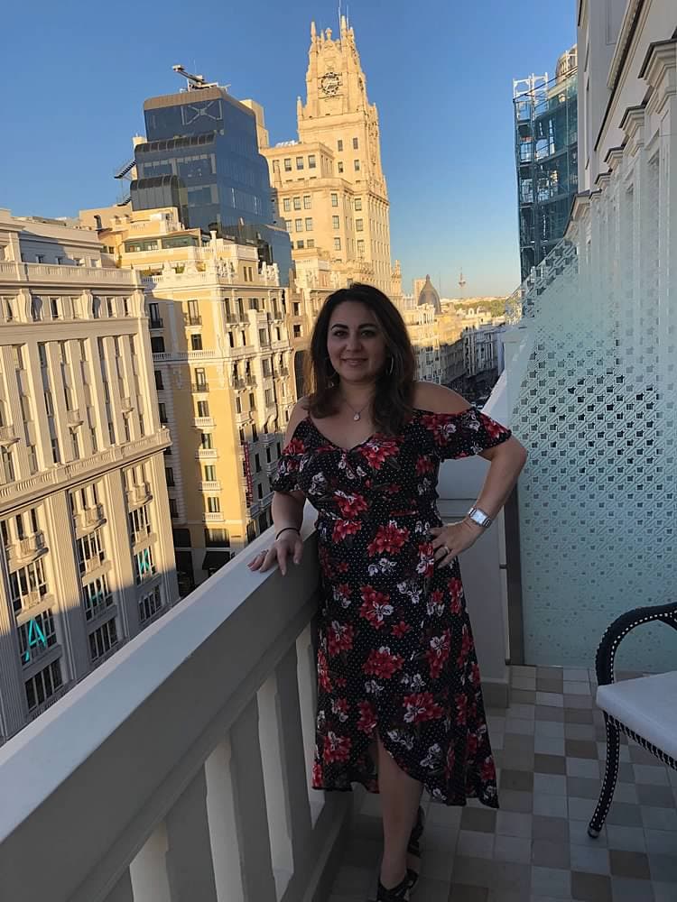 Fora Advisor Marina in a flowered dress on a balcony with buildings in the background.