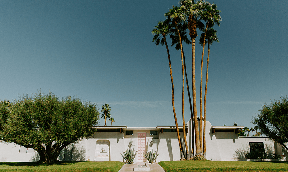 A white Spanish-style home with a pink front door in Palm Springs.