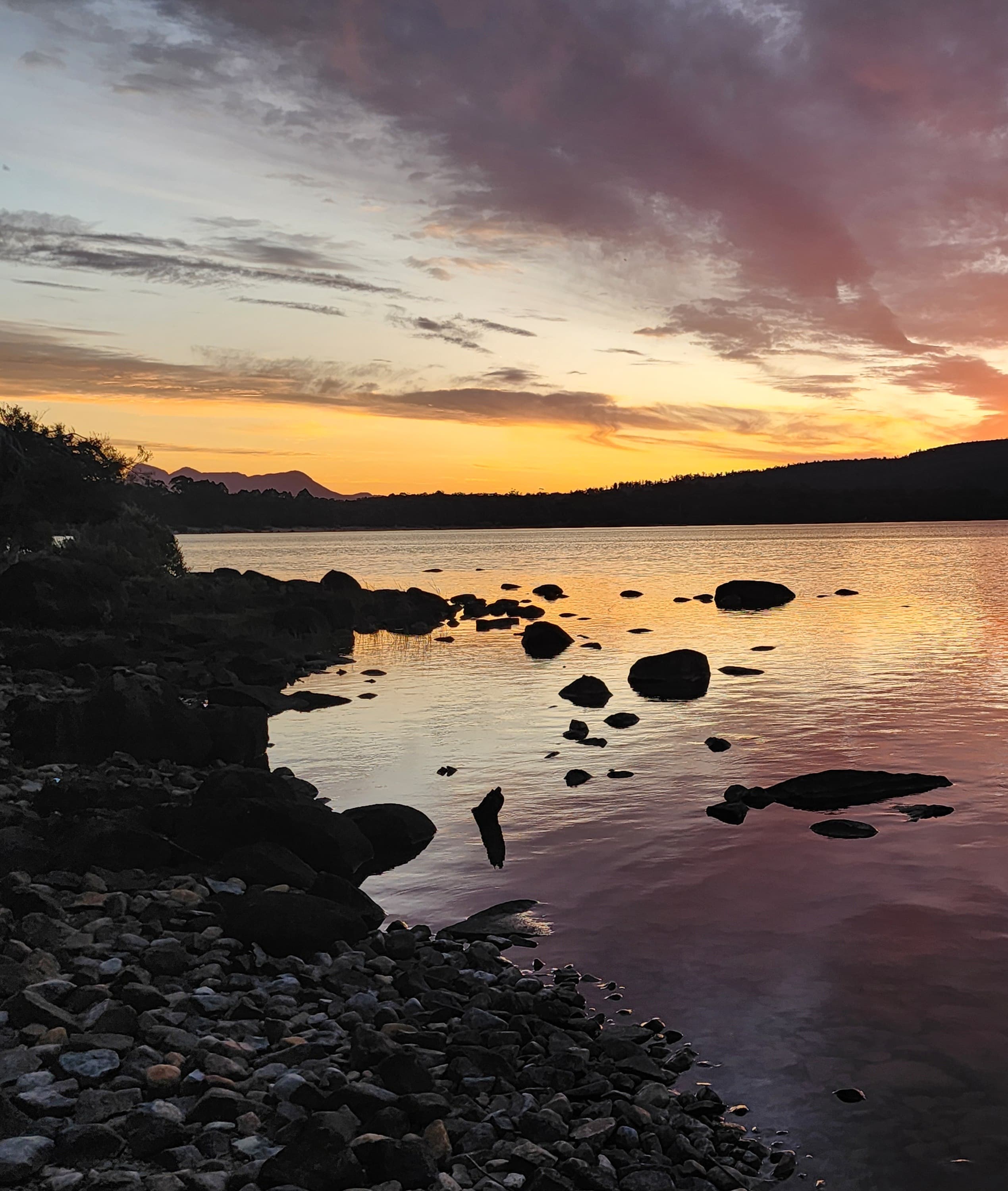 A purple and orange sunset over Lake St Clair from the rocky shoreline