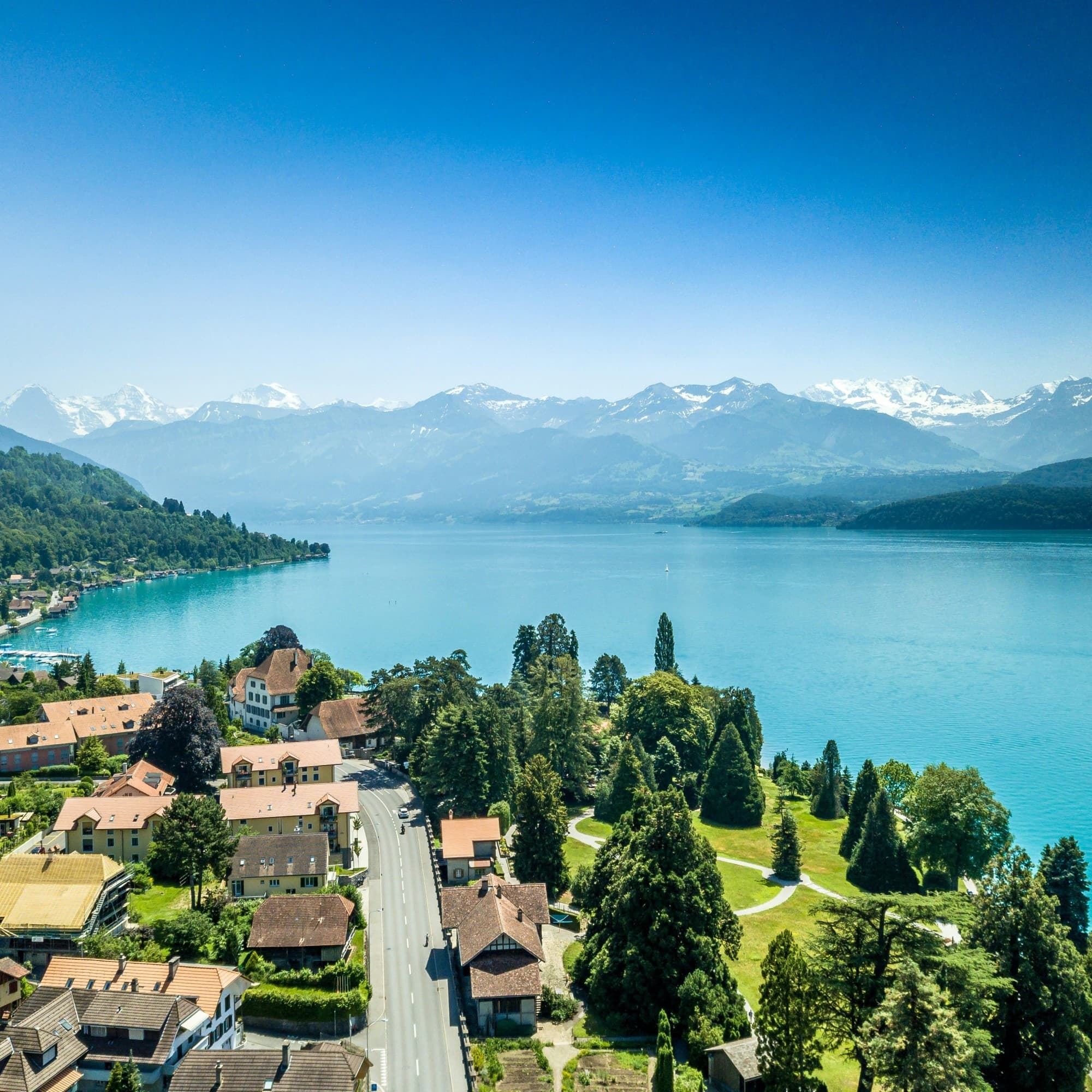Aerial view of a village near a body of water and mountains.