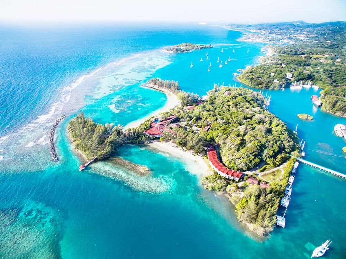 An aerial view of trees and turquoise blue water surrounding an island.