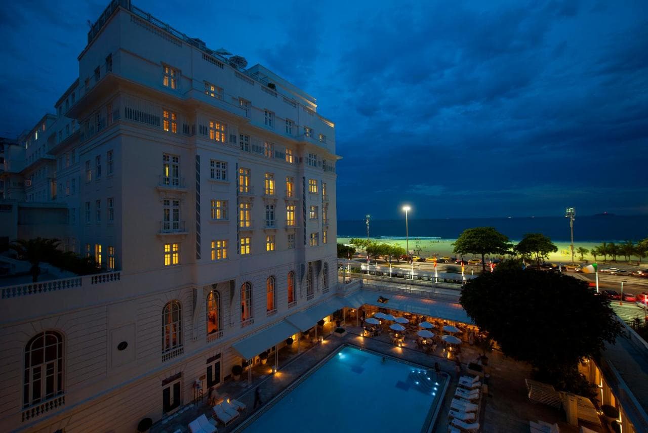 An outdoor pool next to a hotel building at nighttime