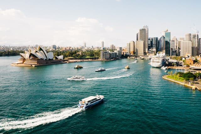 An aerial view of Sydney Harbour, the Opera House, and Sydney's skyline.