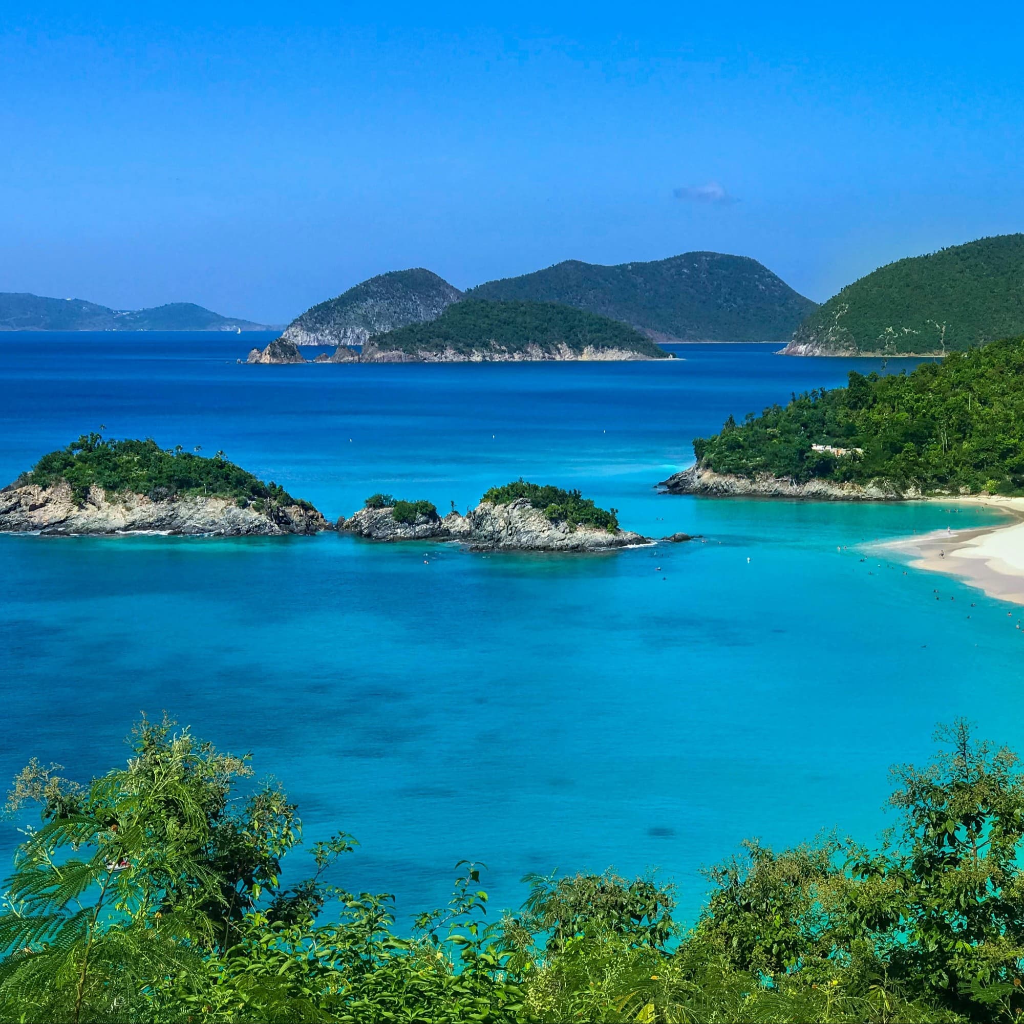 A beautiful view of bright blue water and islands covered with white rocks and trees.